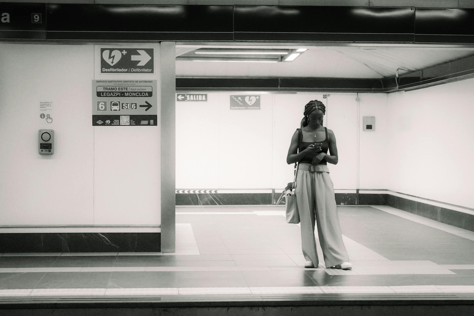 Woman using a phone on a quiet Madrid subway platform