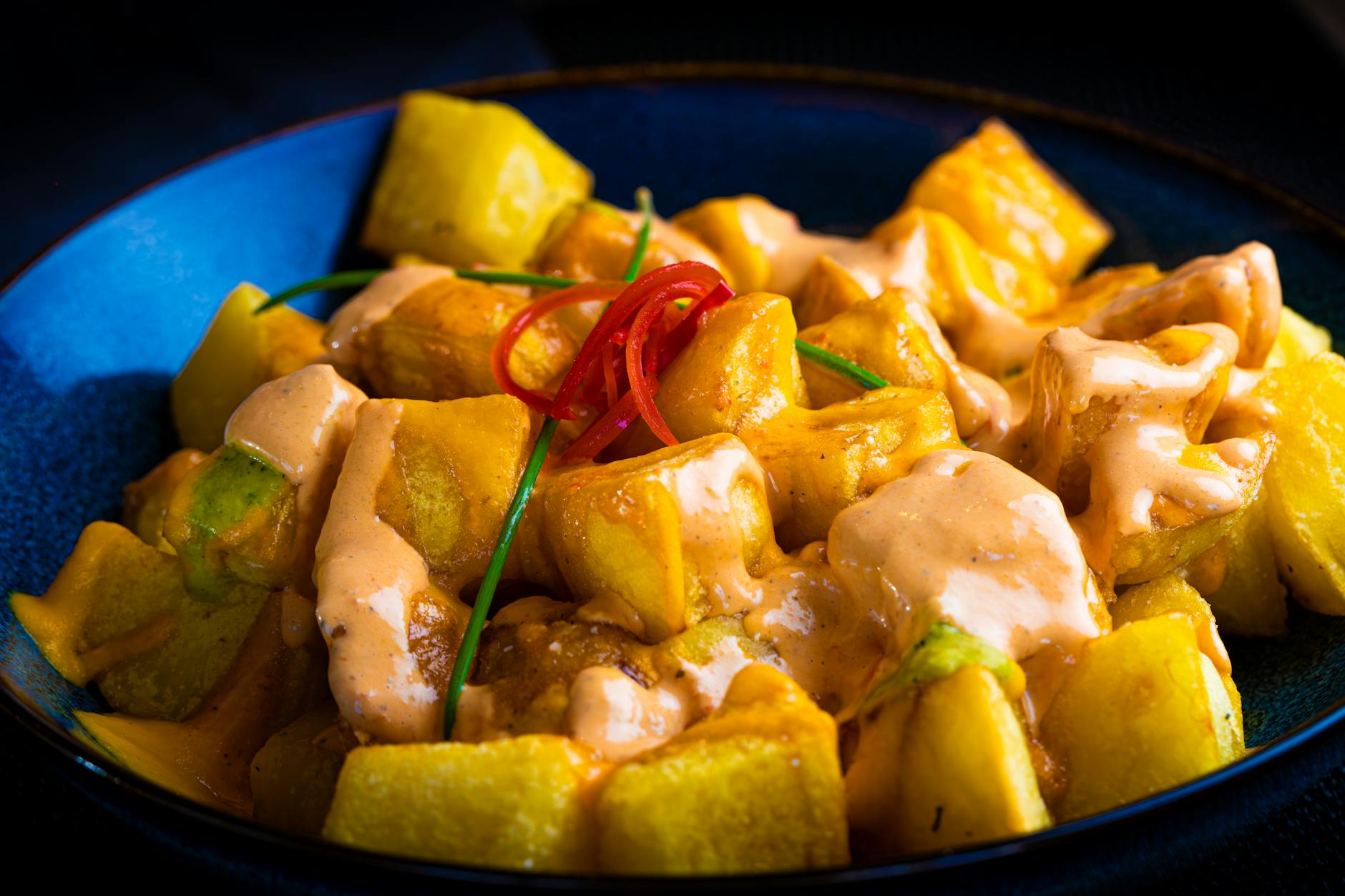 Patatas bravas in a blue bowl