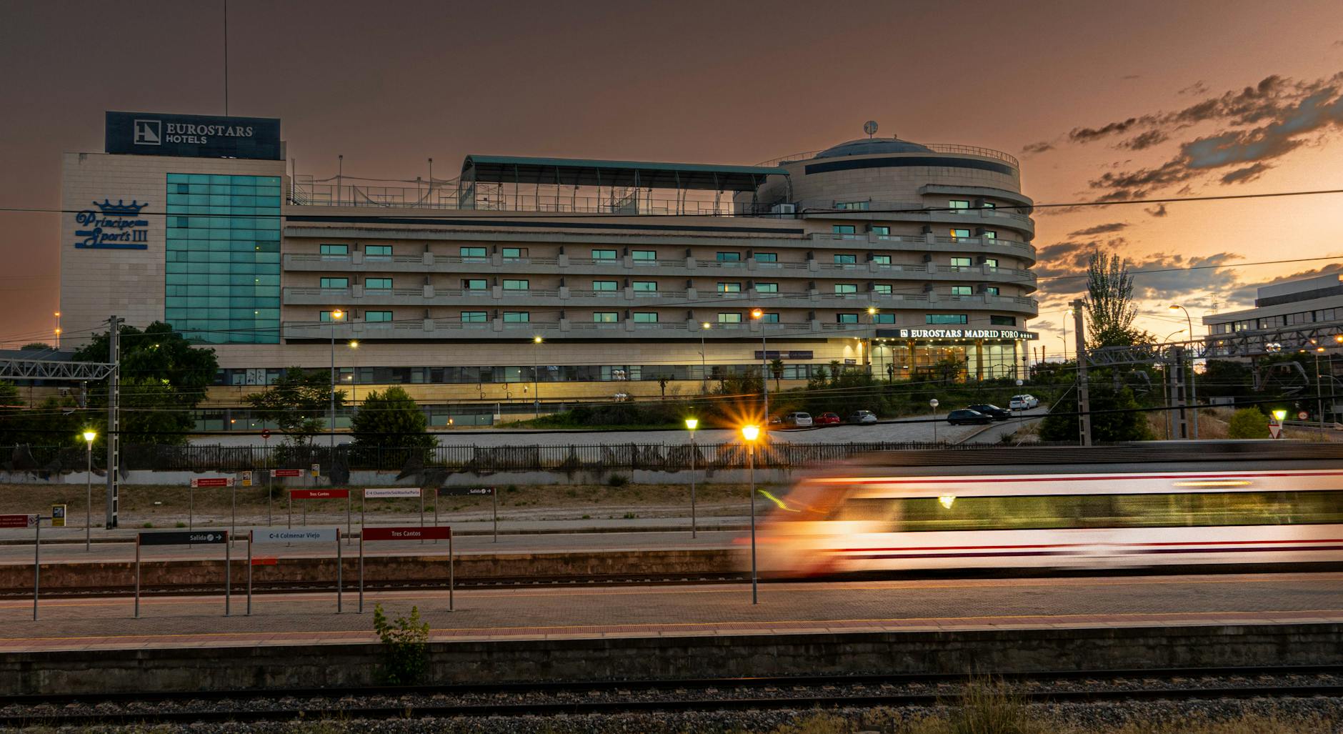 High-speed train passing a Madrid hotel at dusk