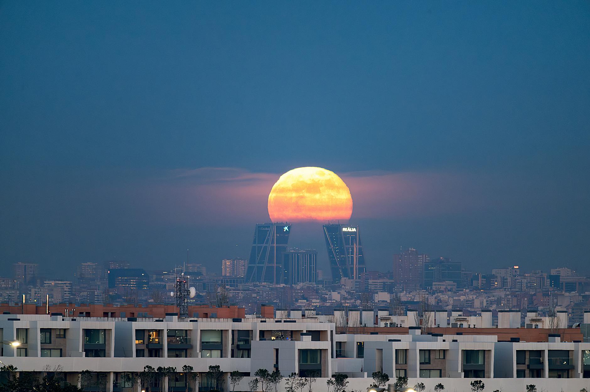 Moonrise over Madrid skyline and illuminated city buildings