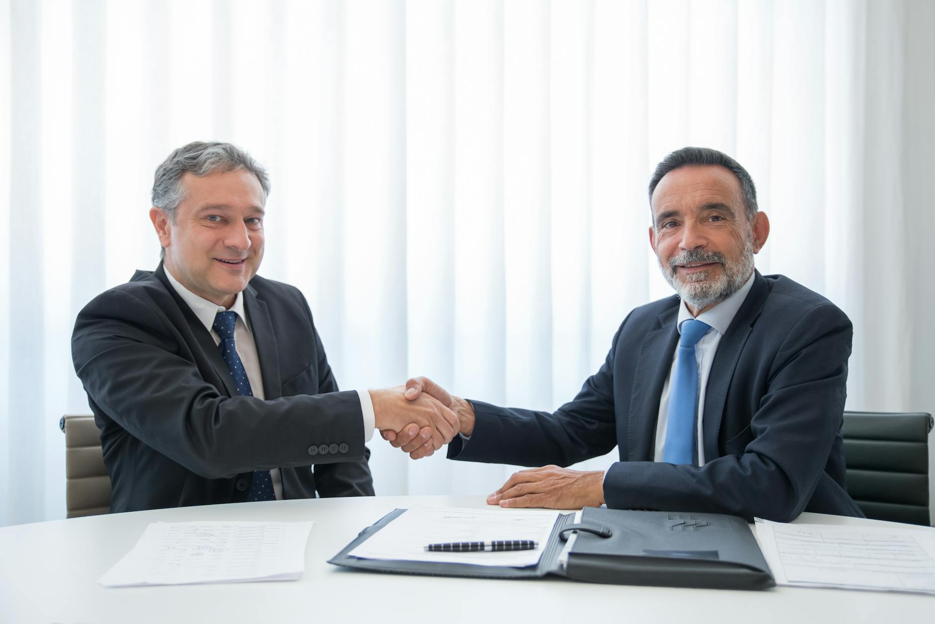 Businessmen shaking hands across an office table