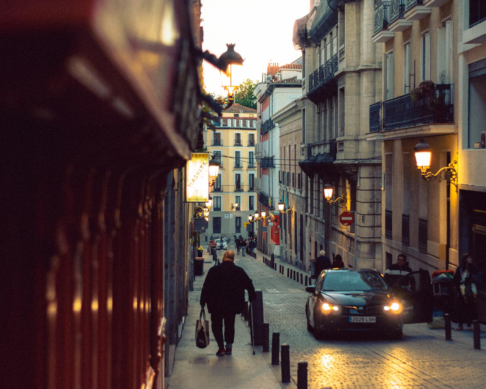 Man walking through a Madrid cobblestone street at twilight