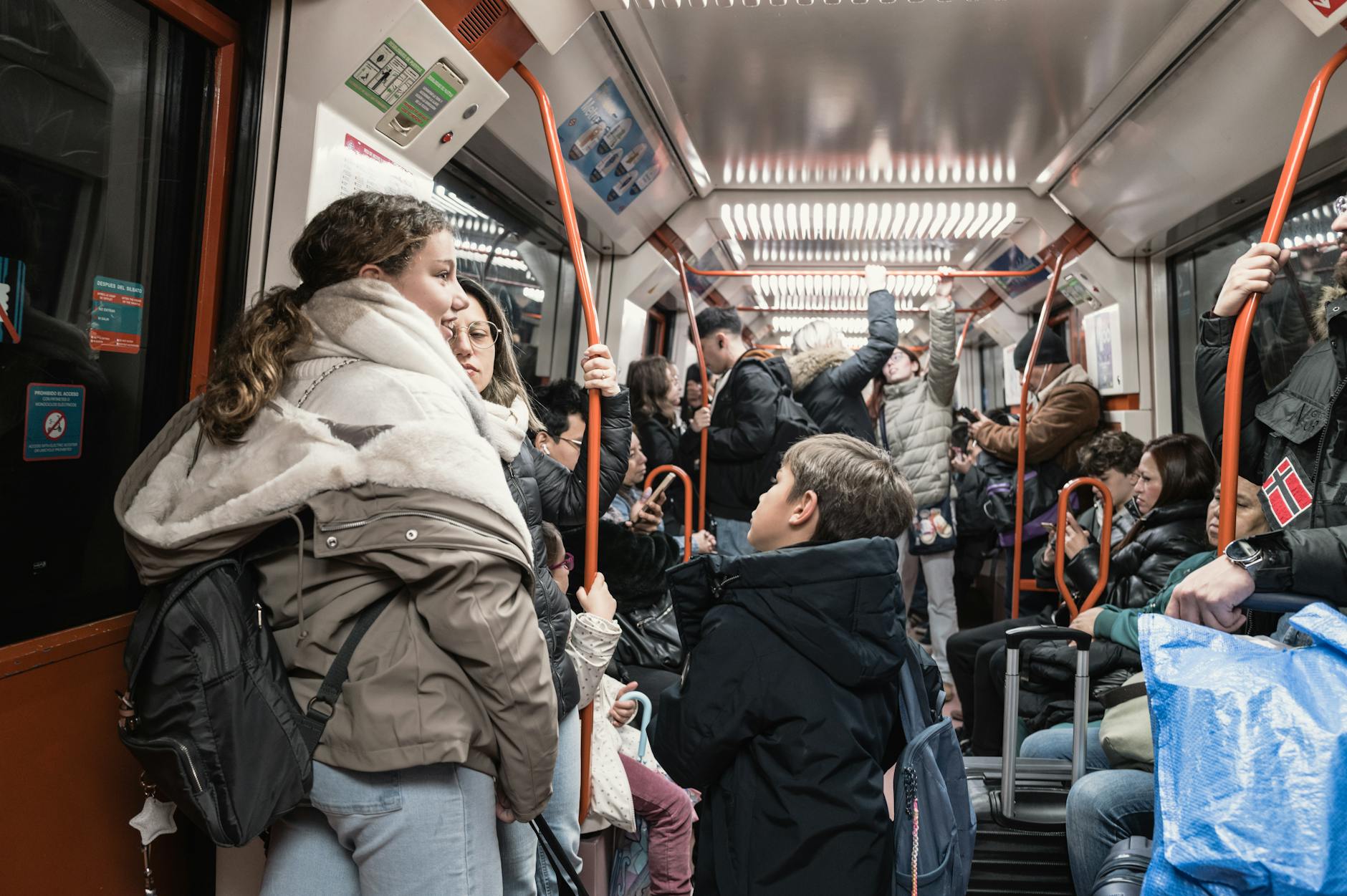 Crowded metro train interior with daytime commuters