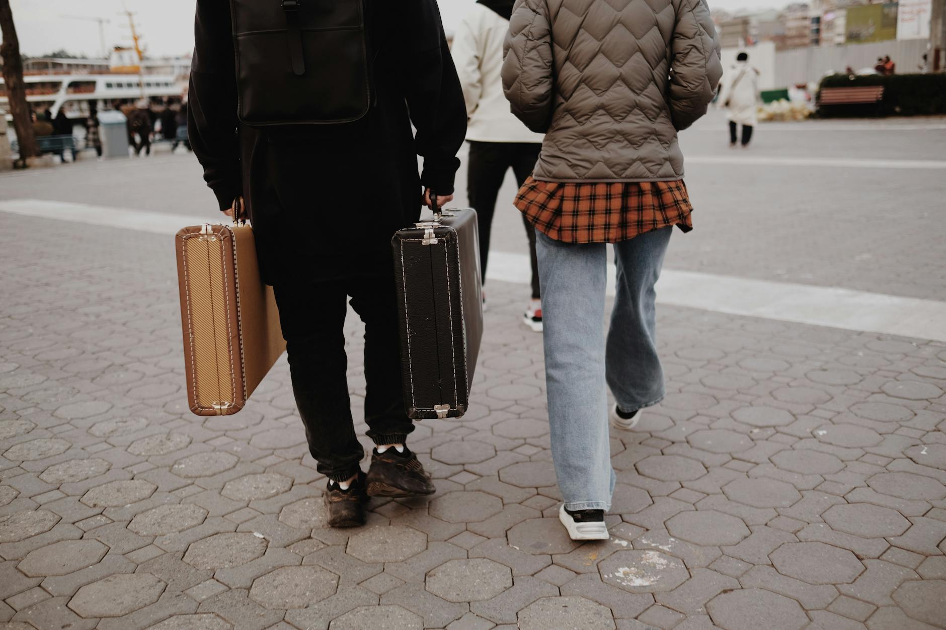 Two travelers walking through a city with vintage suitcases