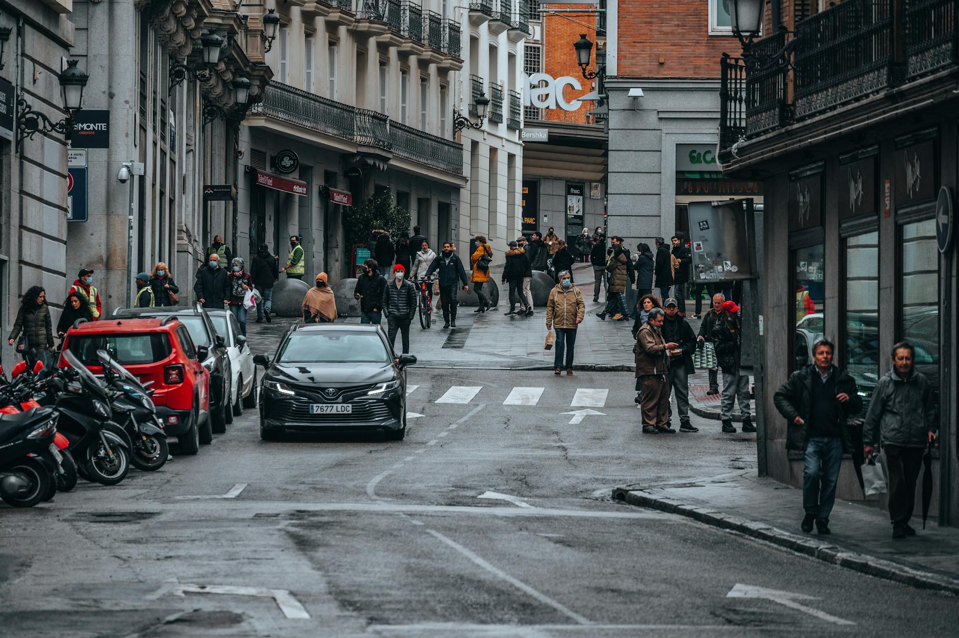 Madrid street with pedestrians, parked cars, and city buildings
