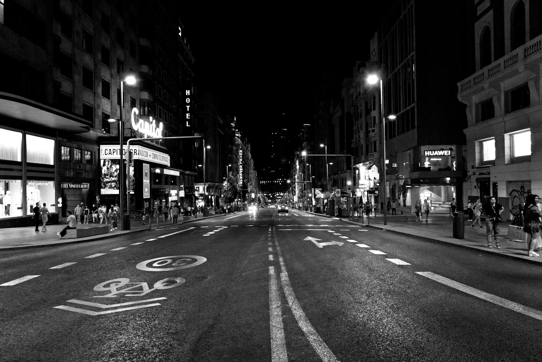Night scene on Gran Via in Madrid with people and neon lights