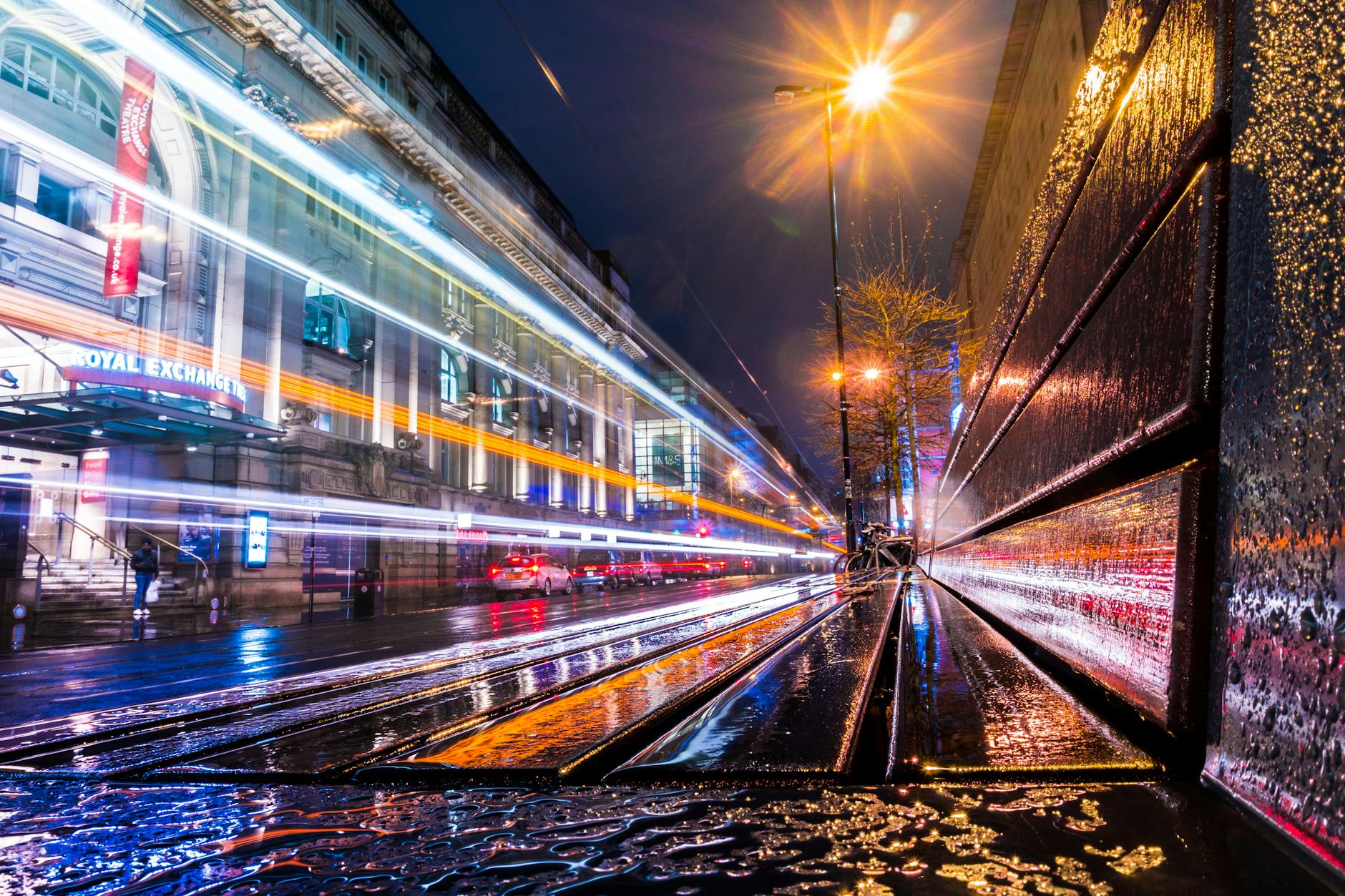 Wet Manchester city street at night with light trails
