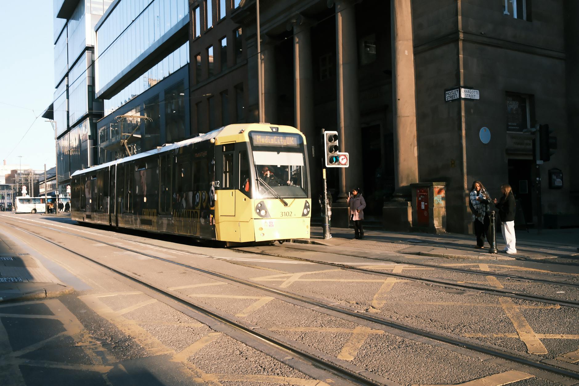 Manchester tram moving through a busy city-centre street
