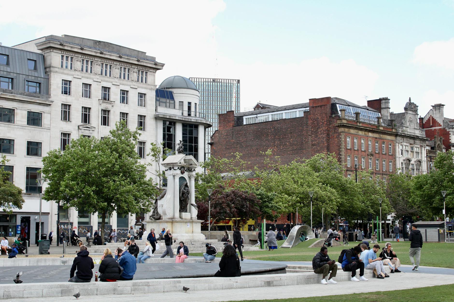 Busy Manchester square with a historic statue and pedestrians