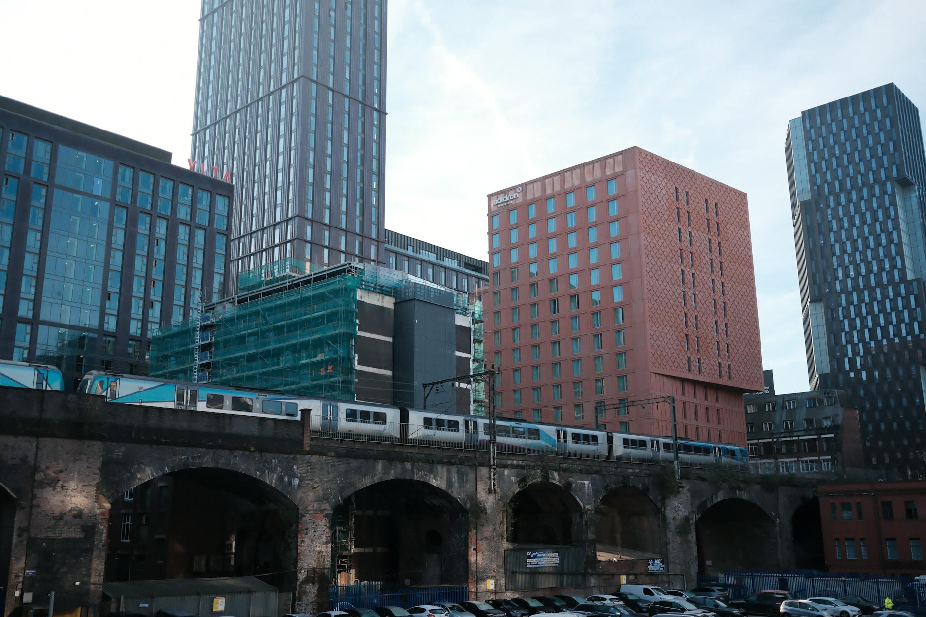 Train moving through modern Manchester buildings for repeat commute planning