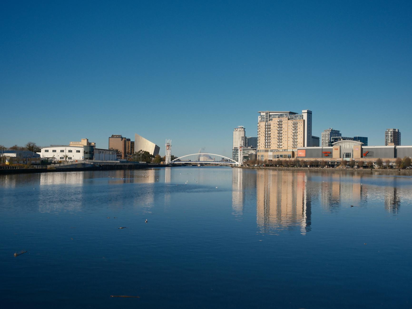 Modern Manchester skyline and bridge reflected on water