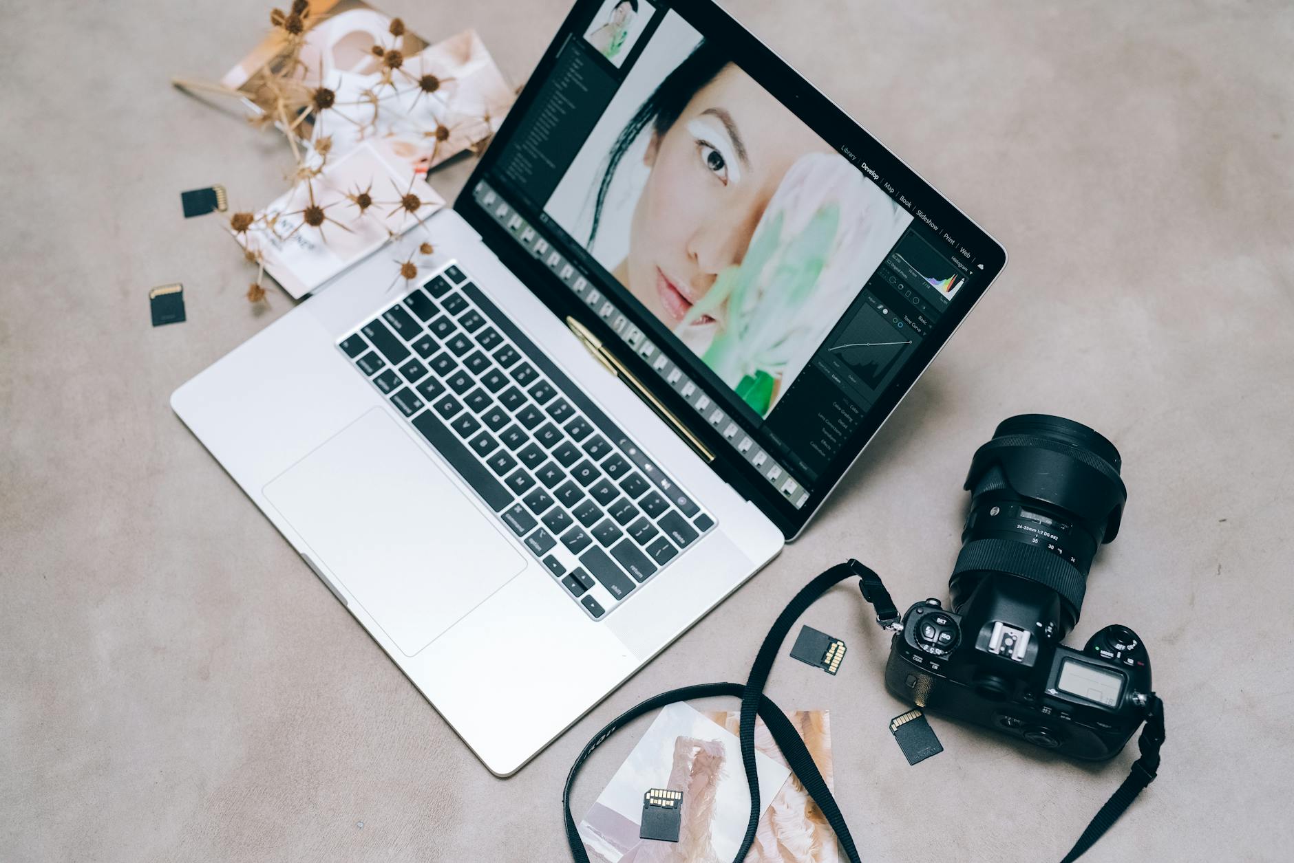 Laptop with photo-editing software beside a camera and memory cards