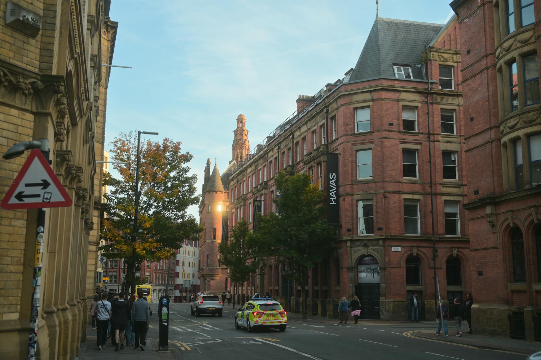 Busy Manchester street at dusk with brick architecture and pedestrians