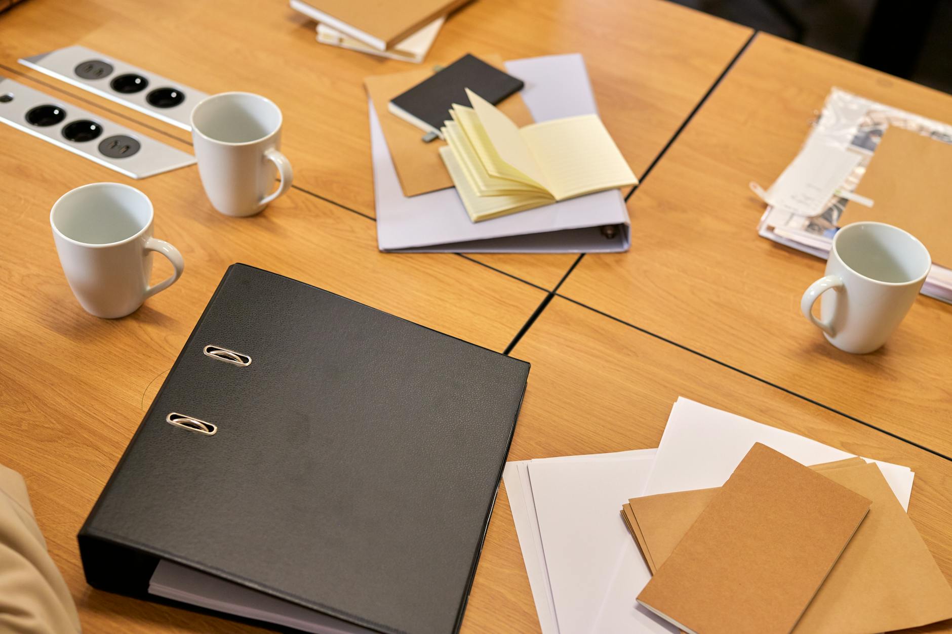 Office desk with binders, papers, and coffee mugs for document review