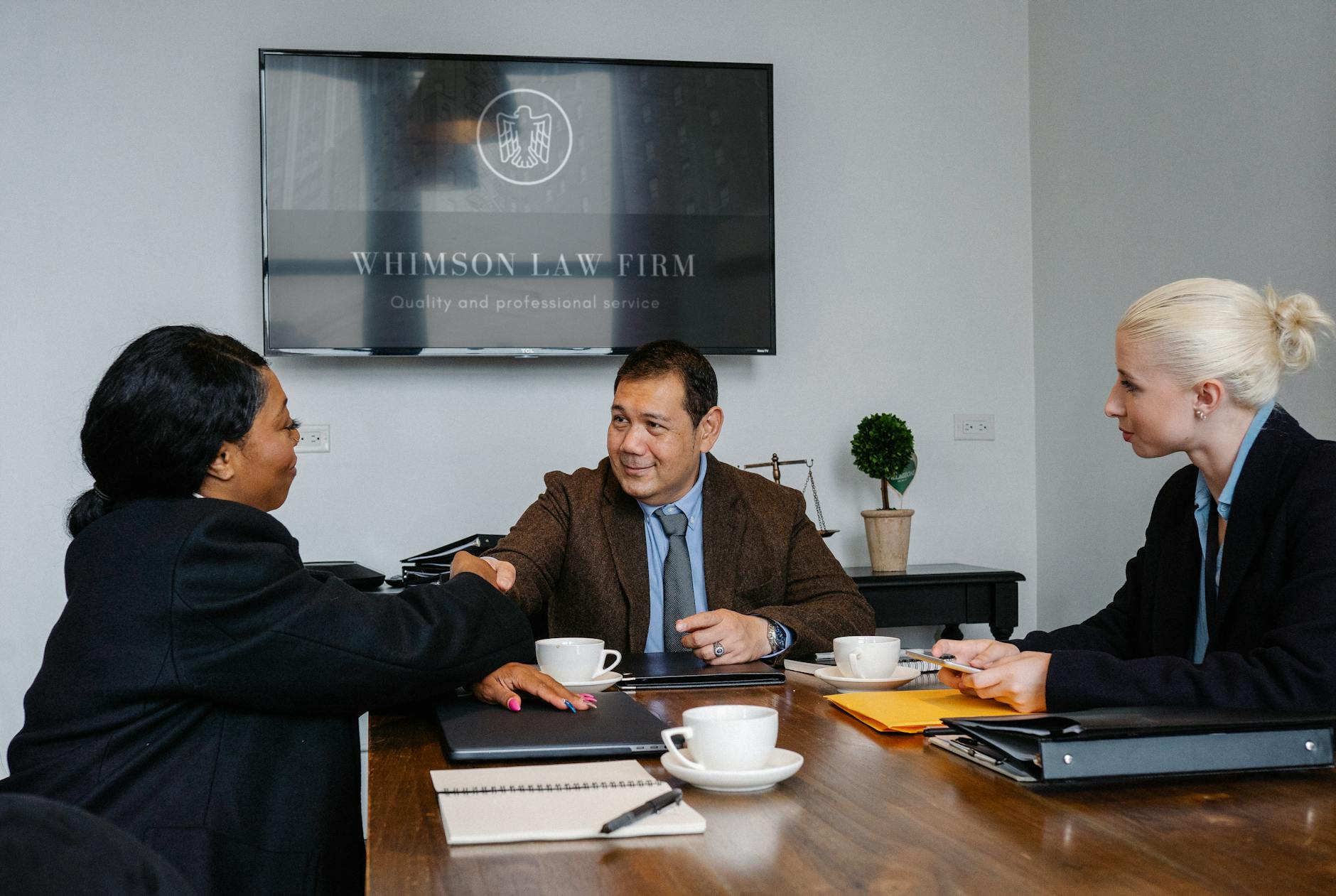Professionals in formal suits discussing documents at a meeting table