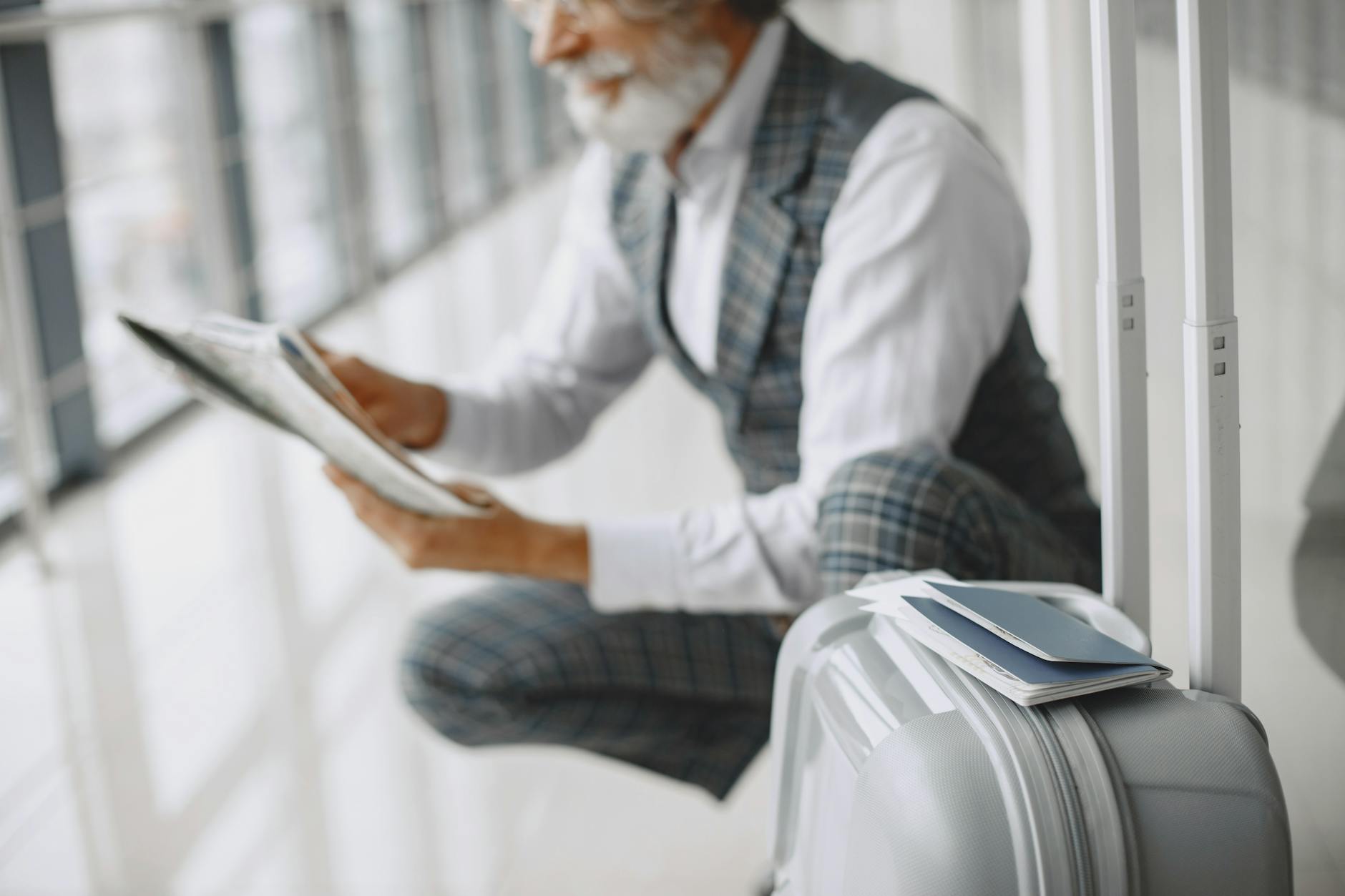 Business traveler with suitcase reviewing papers in an airport terminal