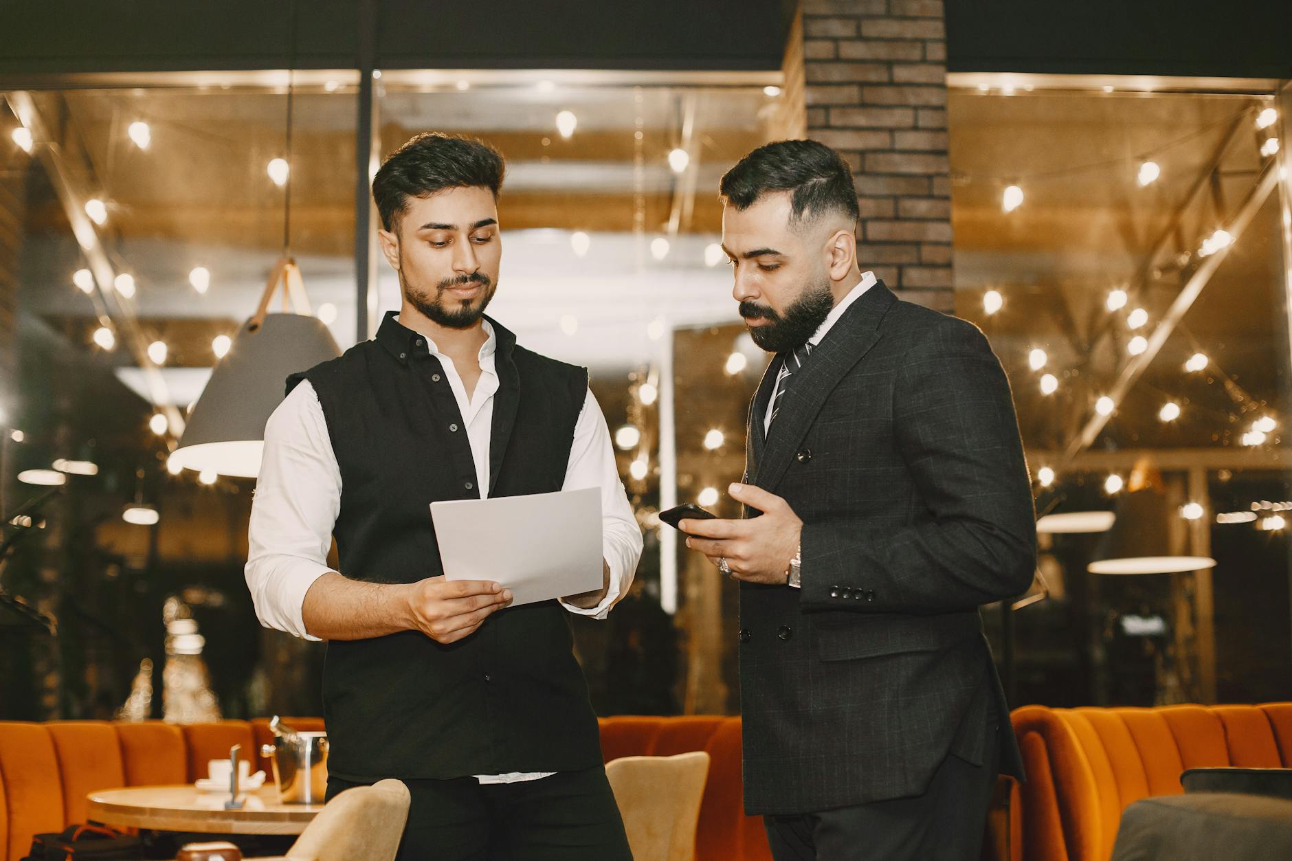 Two businesspeople reviewing documents in a warm restaurant setting