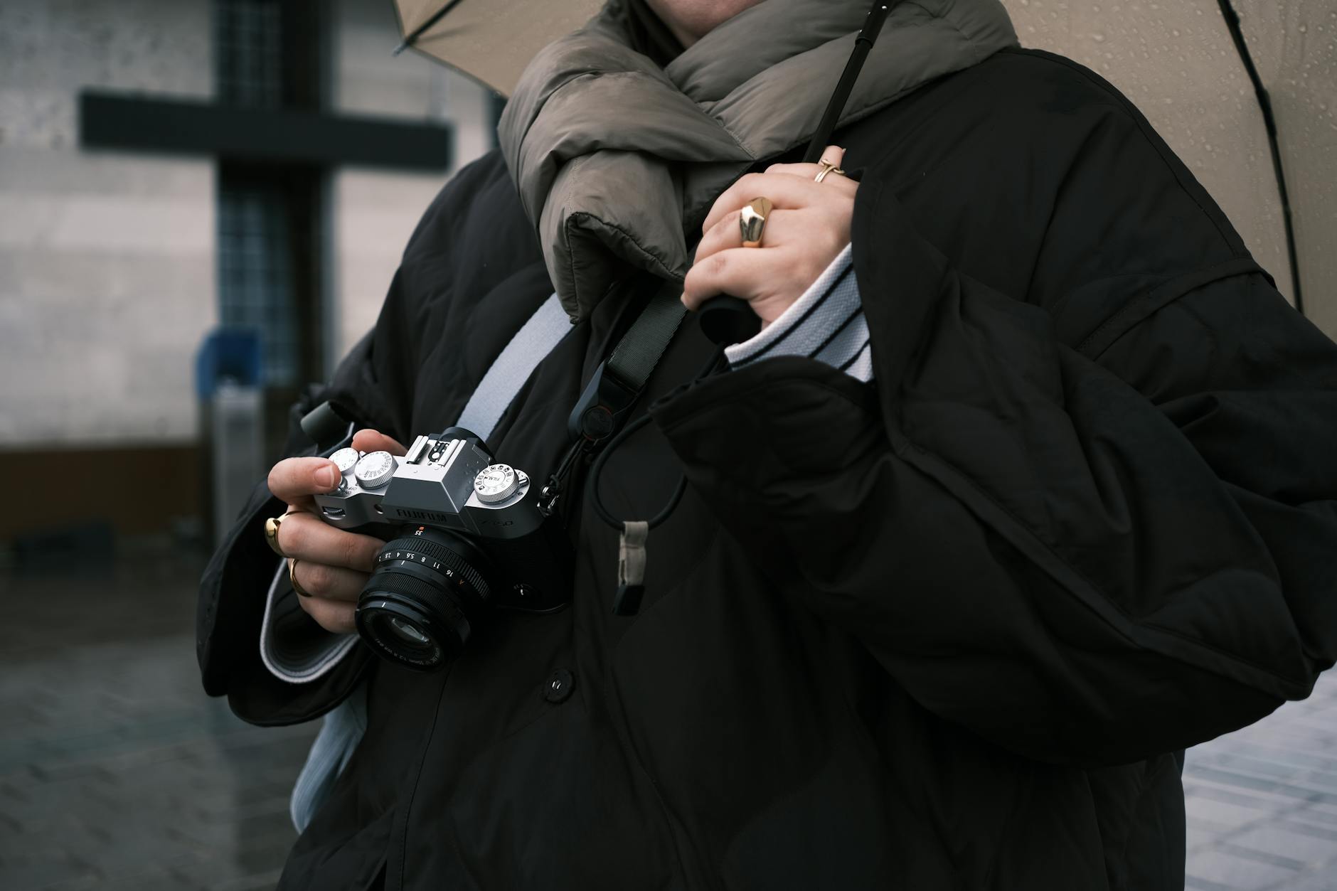 Photographer holding a camera under an umbrella on a rainy street