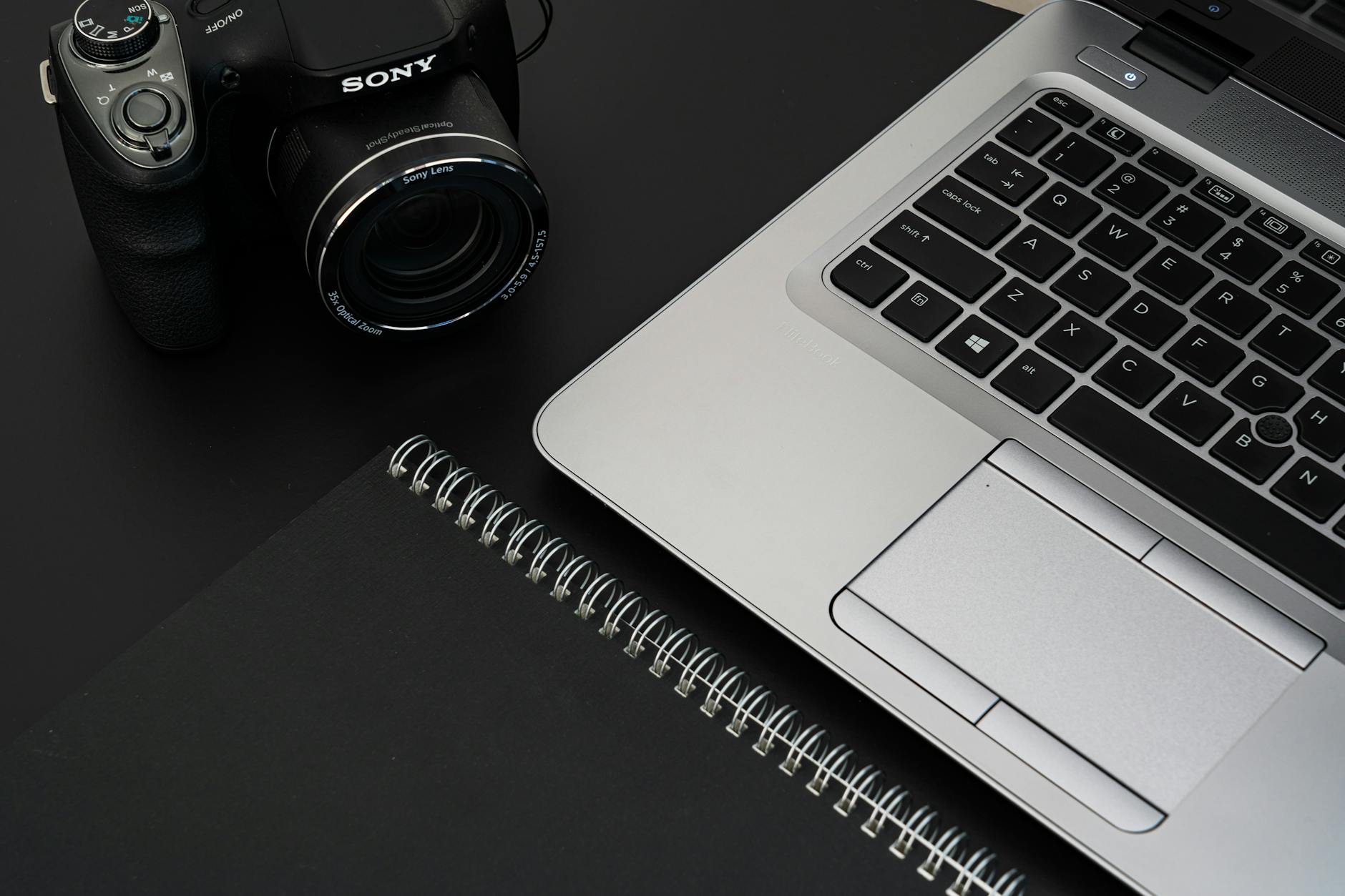 Camera, laptop, and notebook arranged on a work desk
