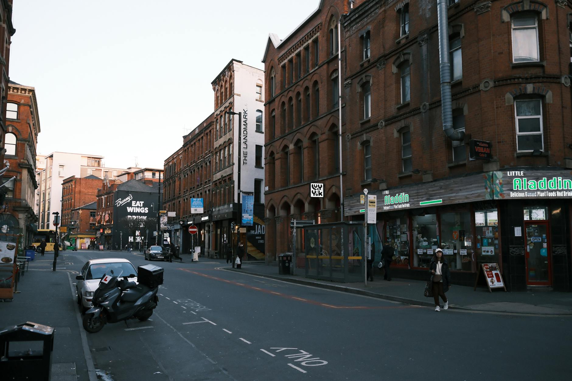 Manchester street lined with red-brick buildings and shops