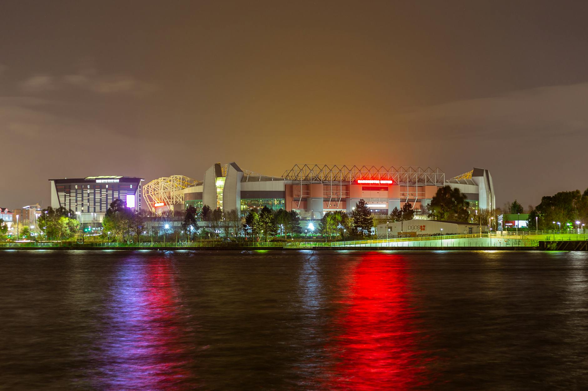 Old Trafford stadium reflected in water at night in Manchester