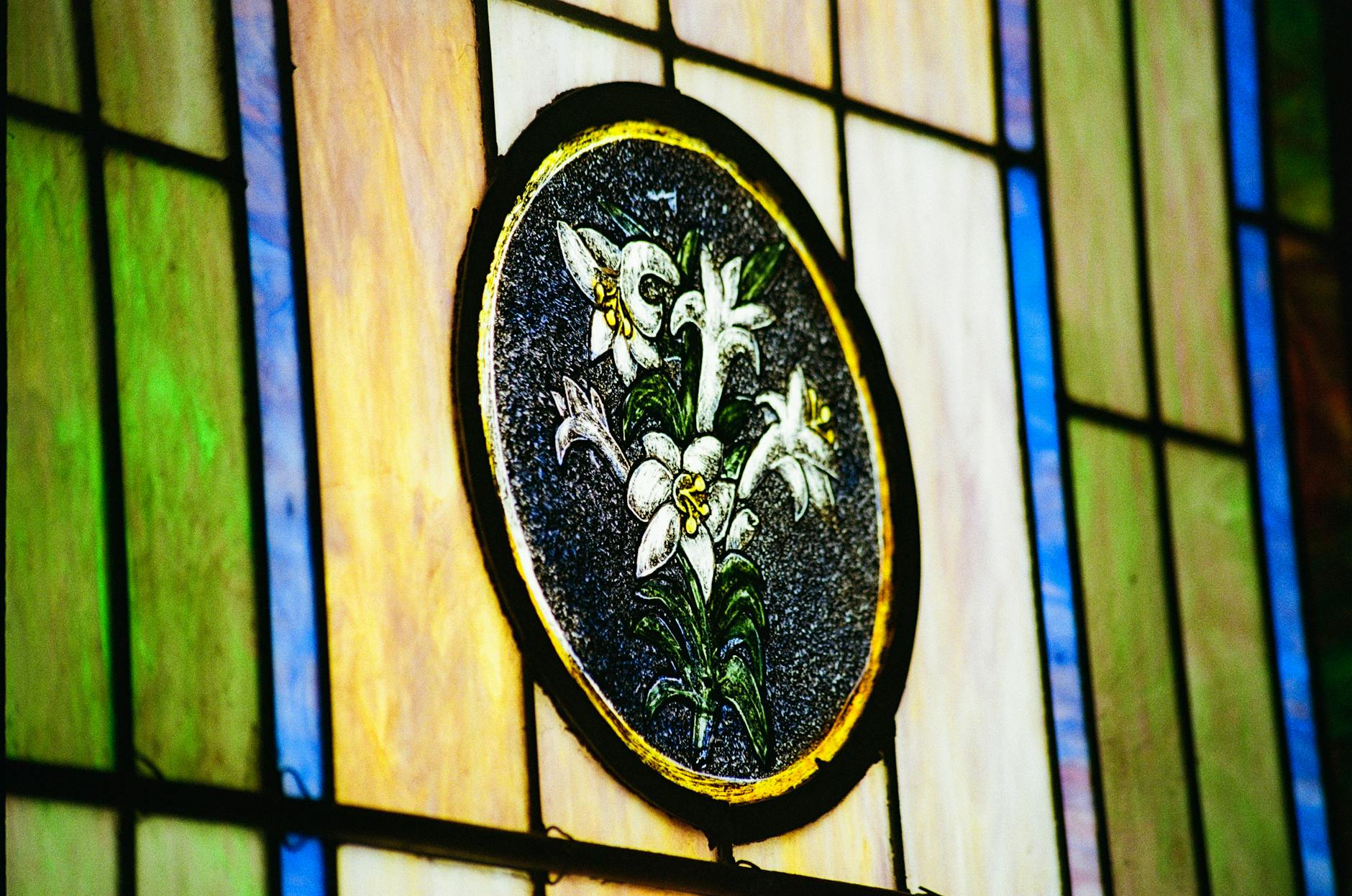 Stained glass window with Easter lilies in a church setting