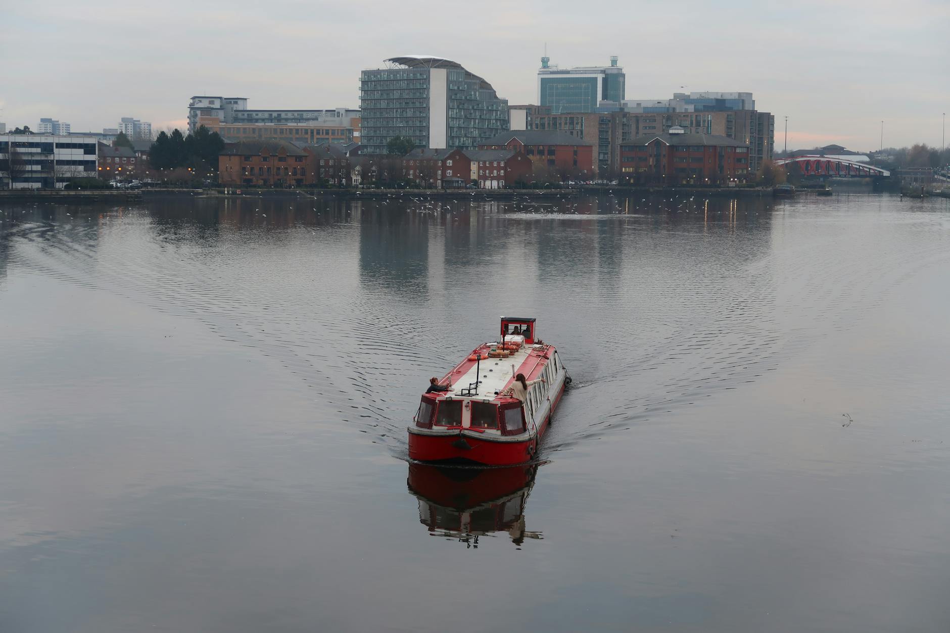 Red boat on calm water at Salford Quays