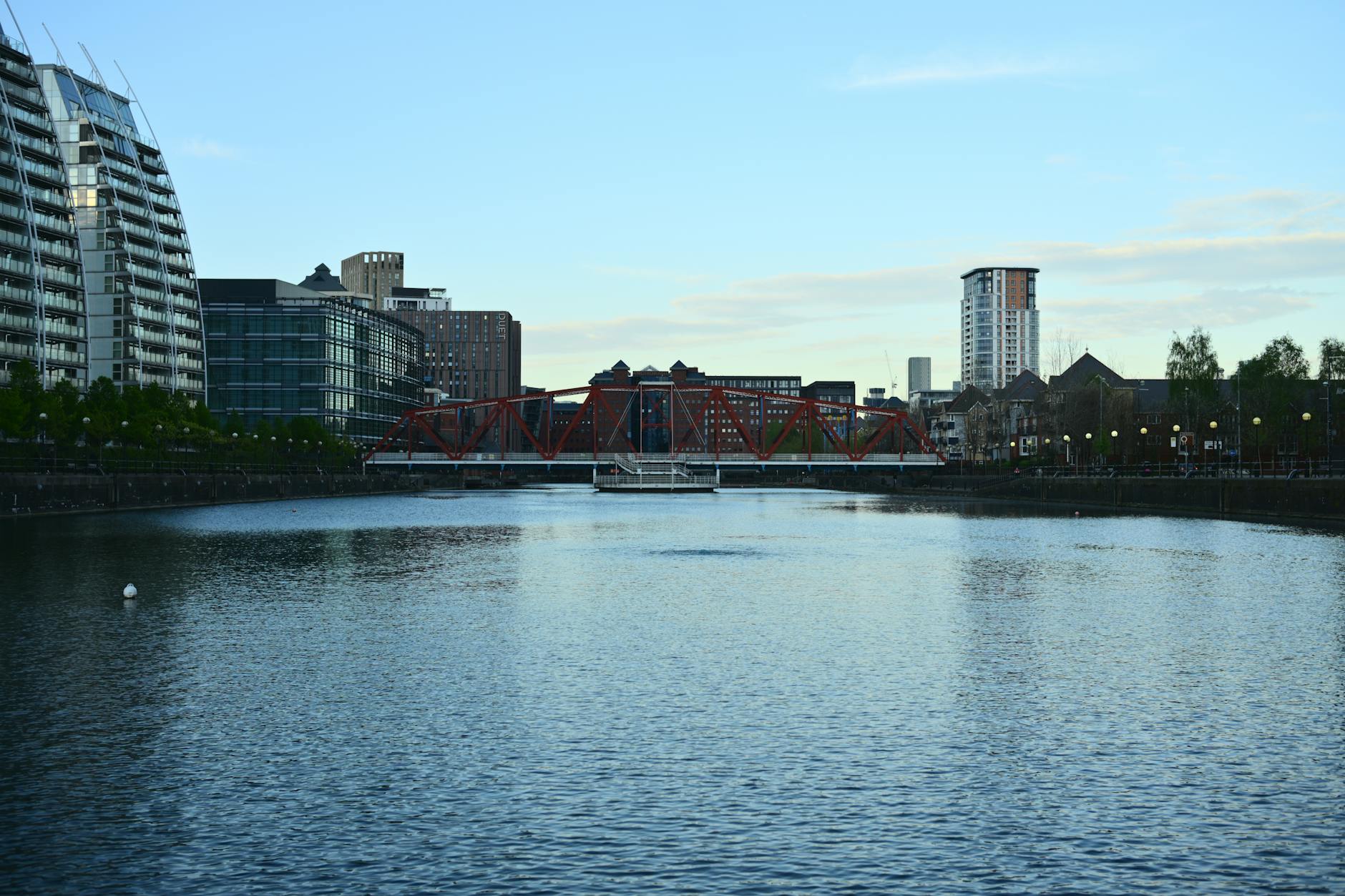 Manchester riverside cityscape with a red bridge at dusk