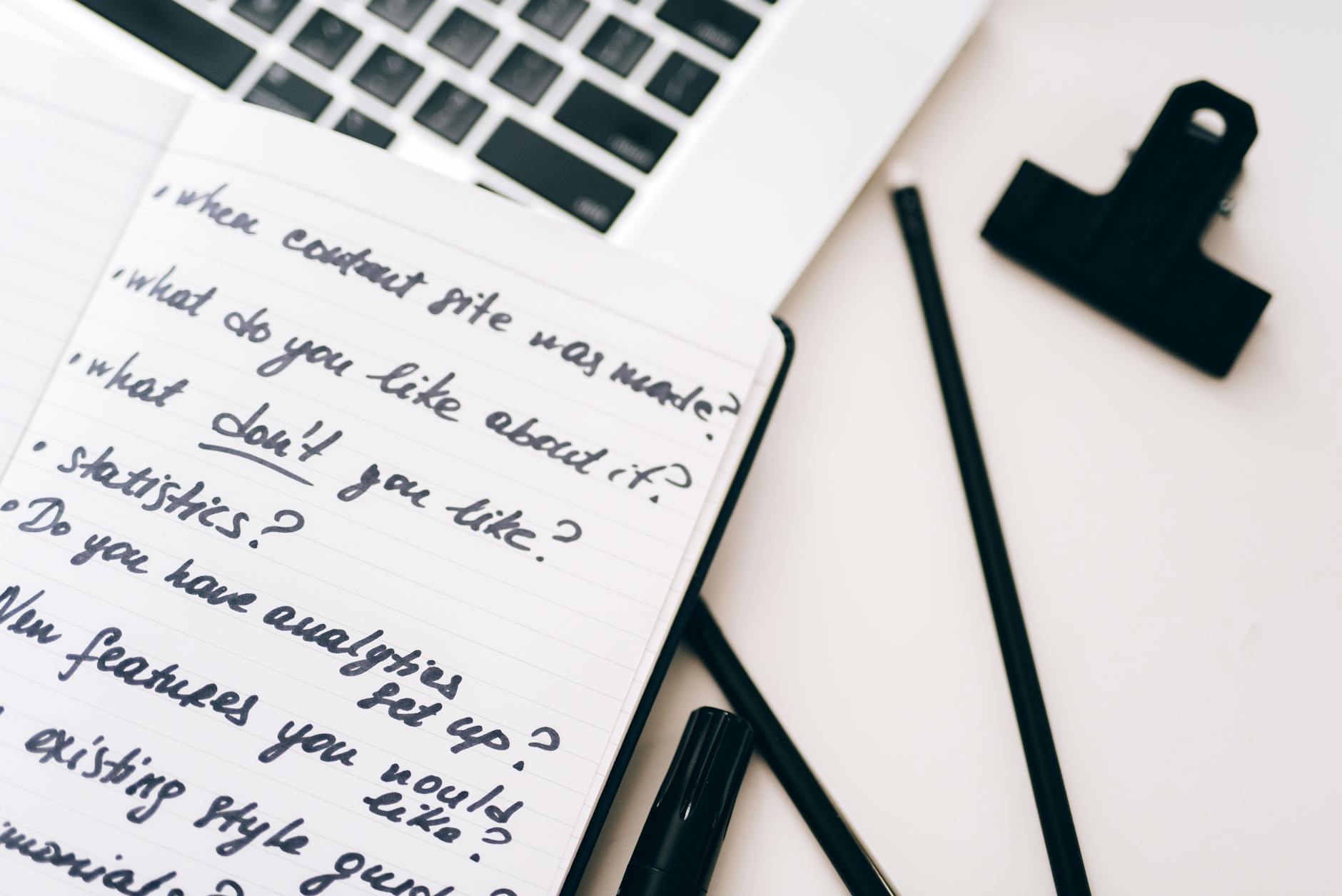Notebook with handwritten follow-up notes beside a laptop