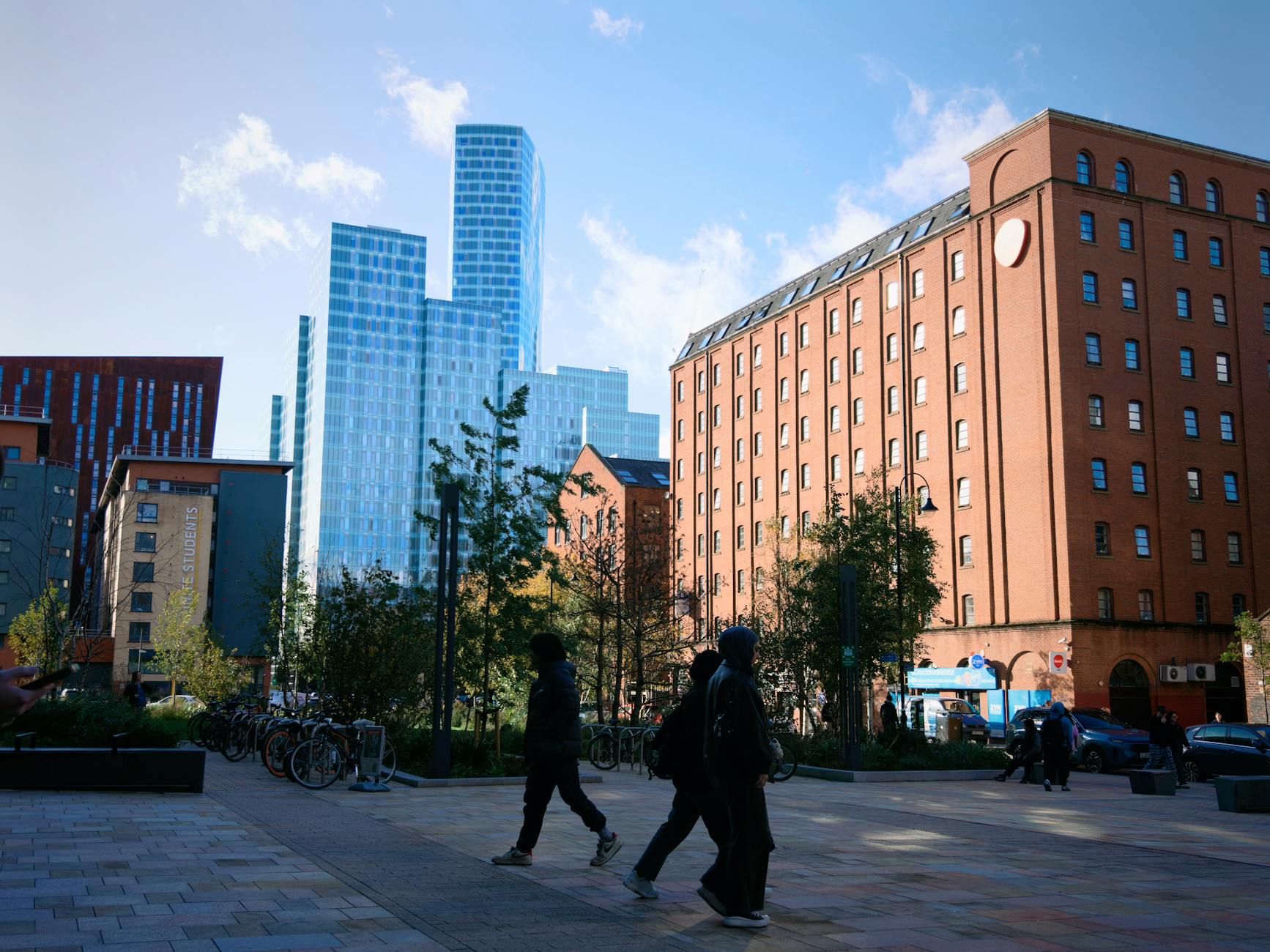 Manchester city-centre pedestrians beneath modern skyscrapers