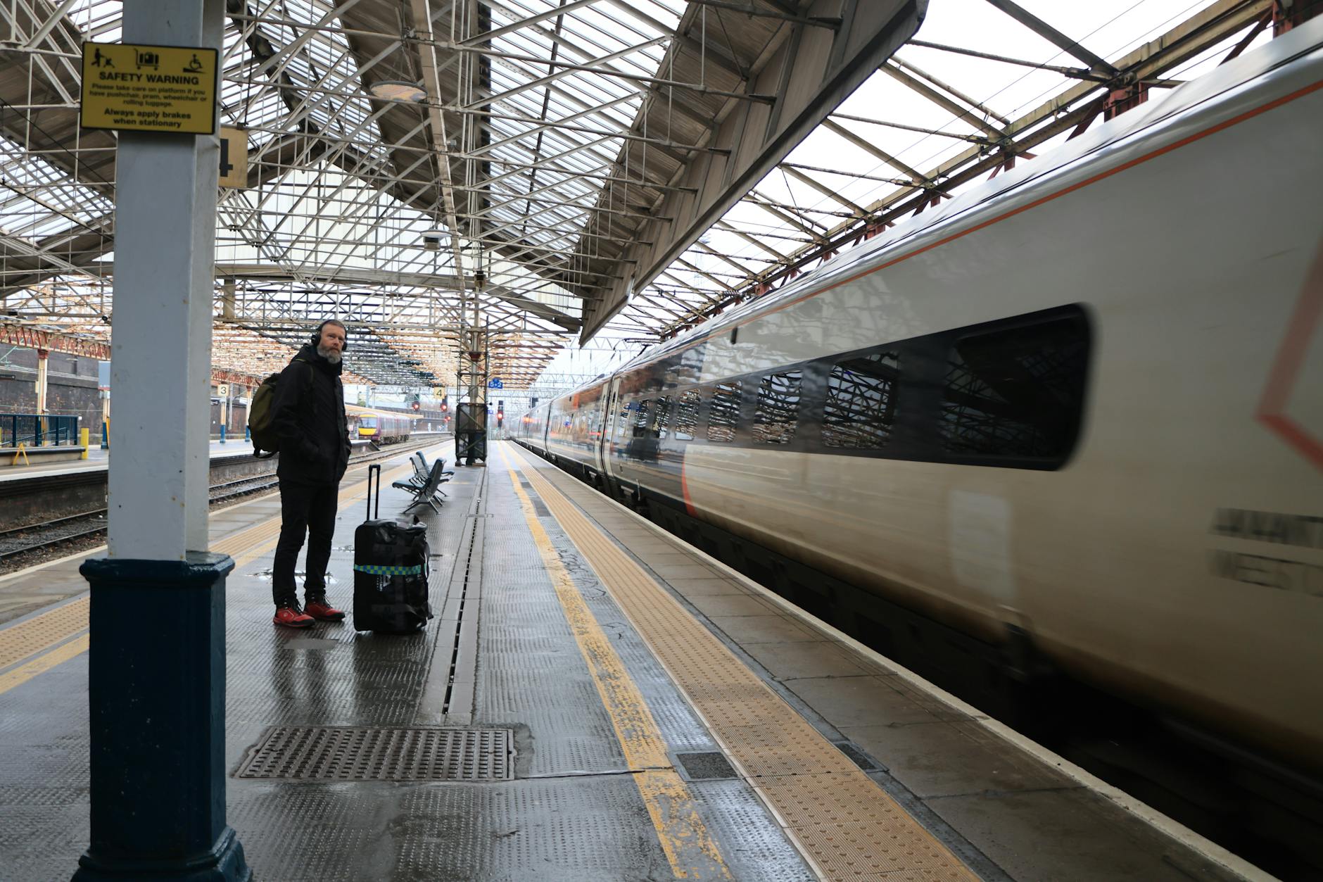 Traveler with suitcase waiting on a UK railway platform
