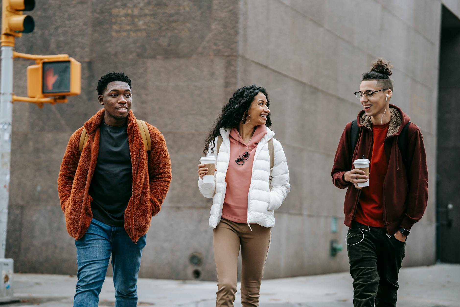 Young friends walking on a city street with takeaway coffee