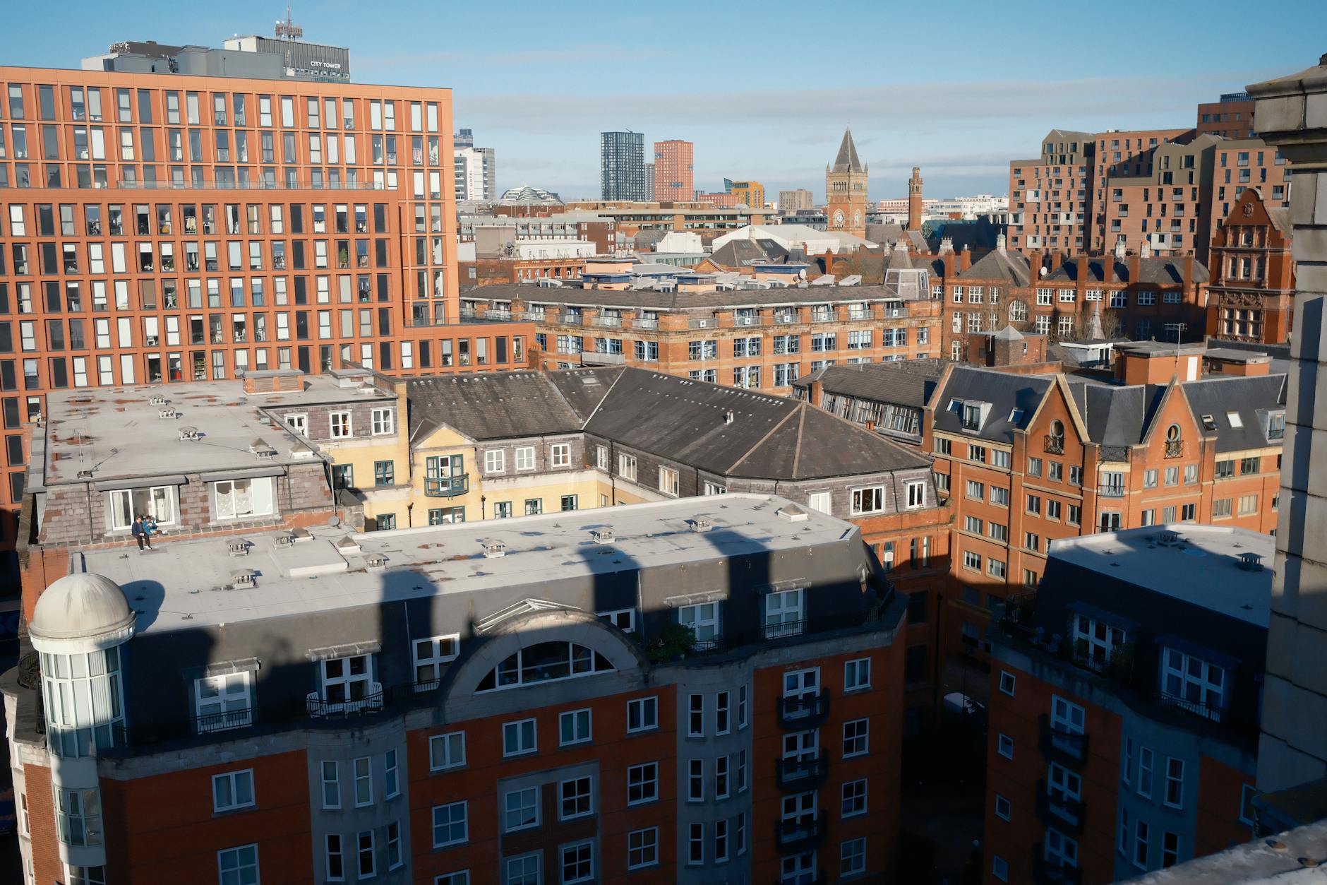 Manchester skyline with red brick buildings under blue sky