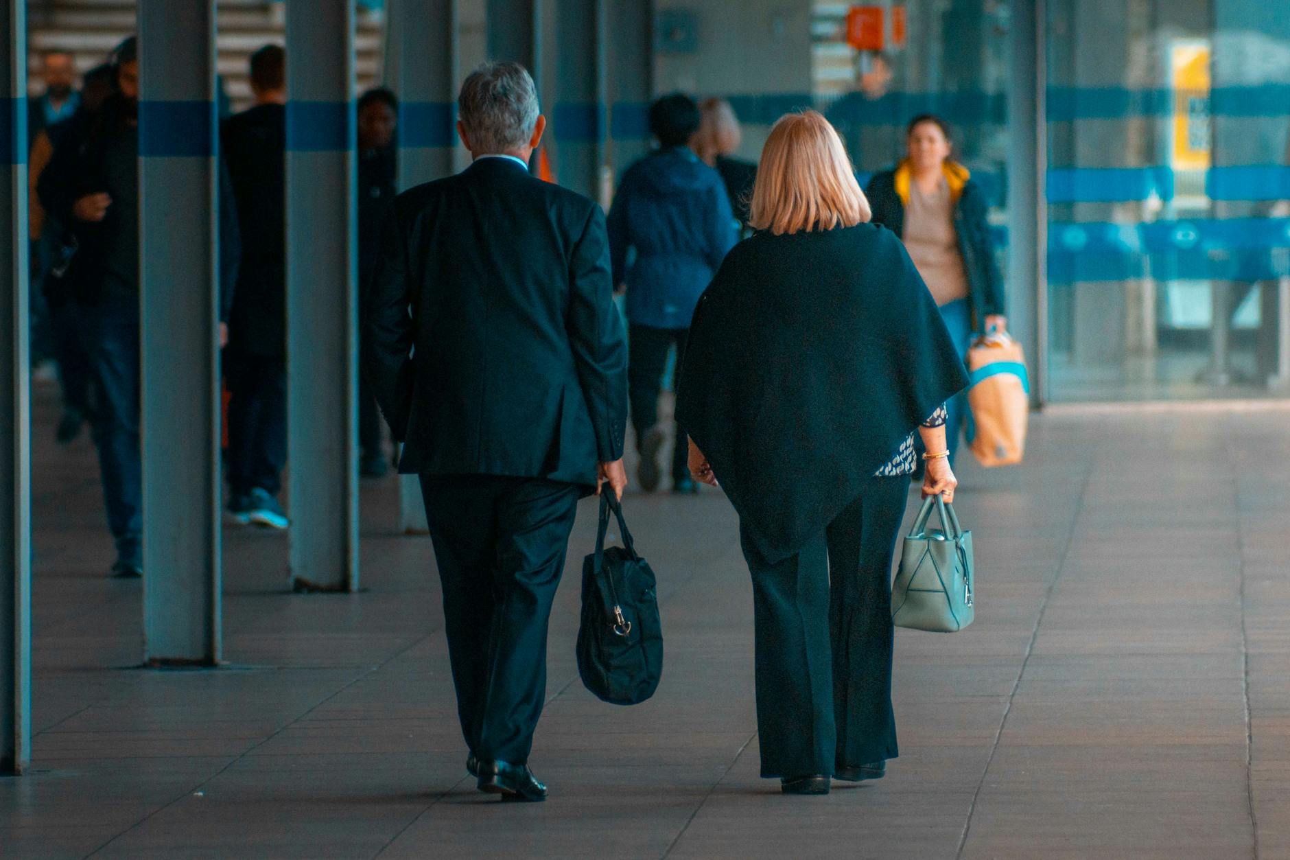 Travelers walking with suitcases through a busy train station