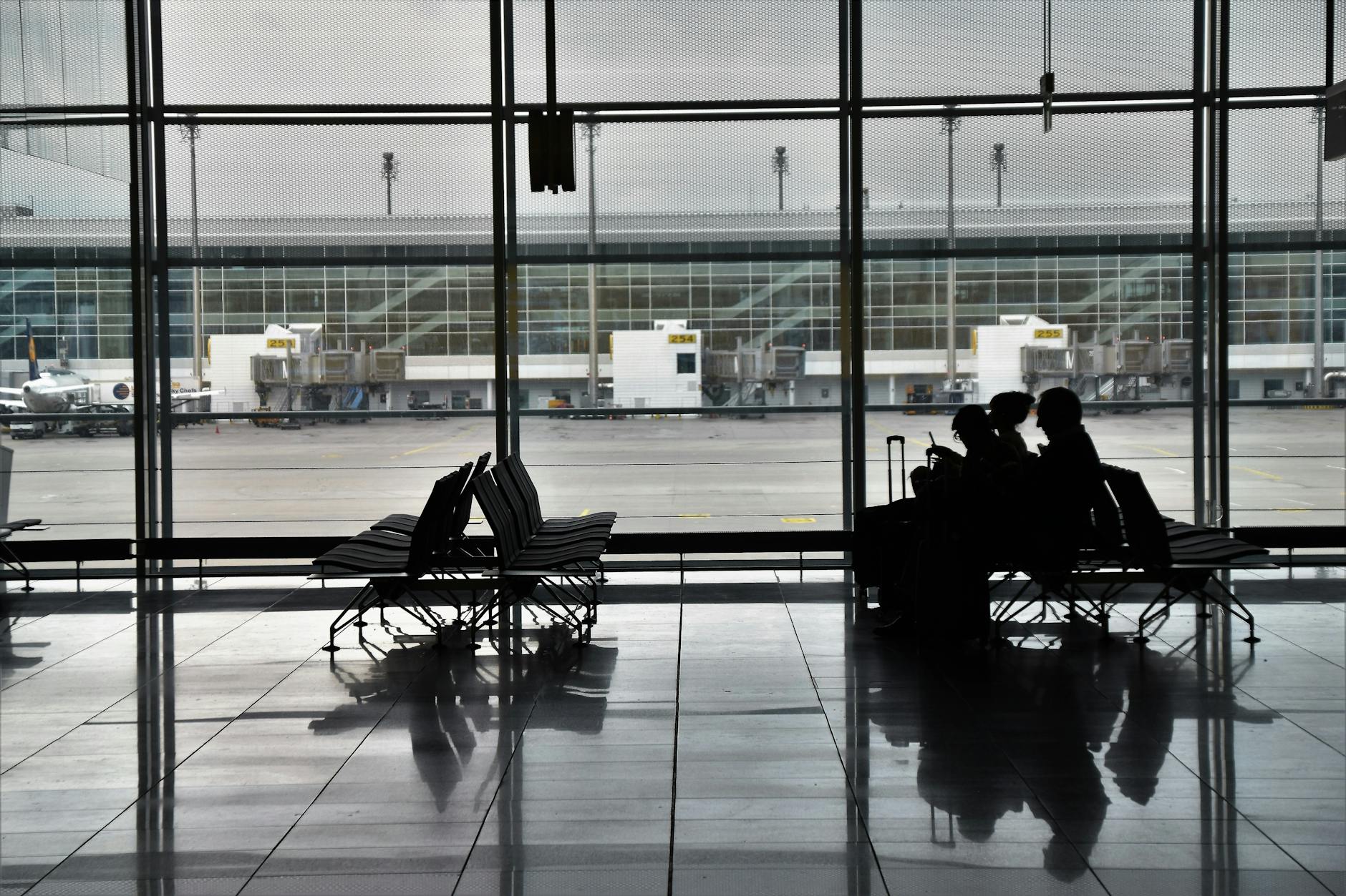 Passengers seated with luggage in an airport waiting area