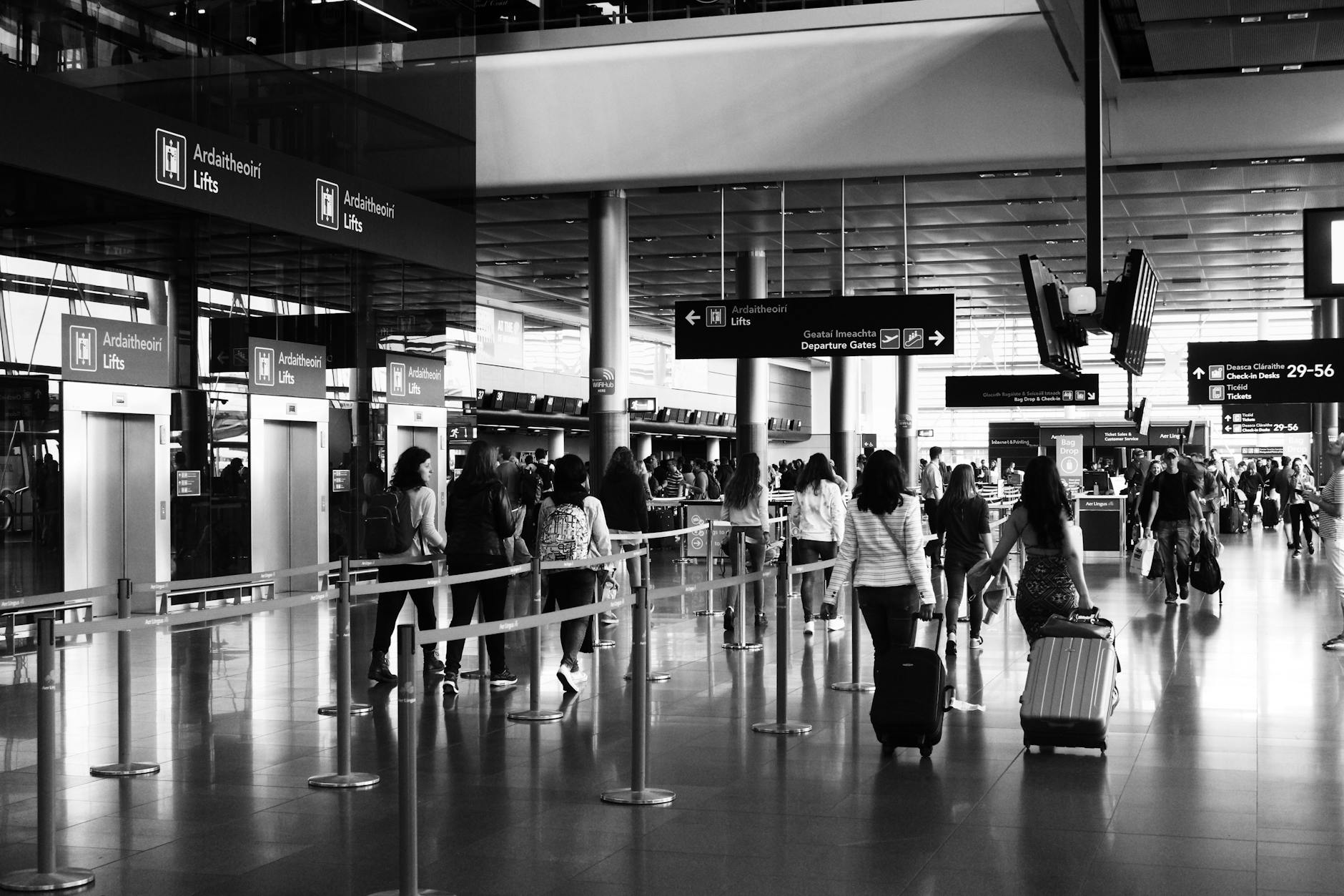 Travelers walking with luggage through a busy airport terminal