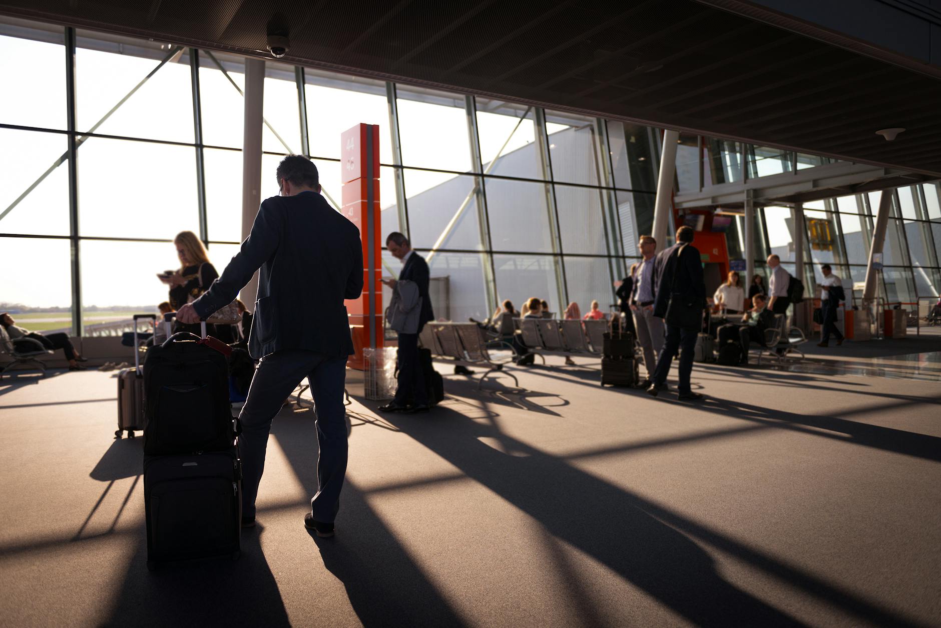 Travelers with carry-on luggage in a busy airport terminal
