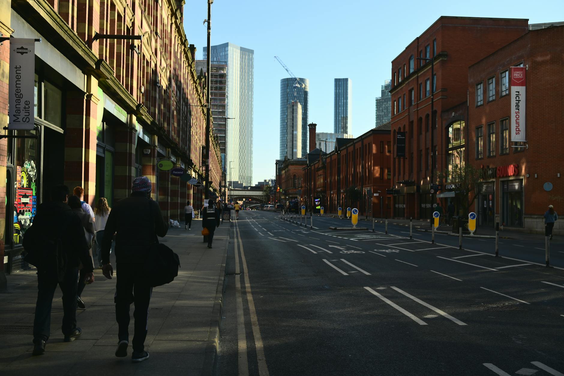 Manchester street with pedestrians and modern towers under a clear sky
