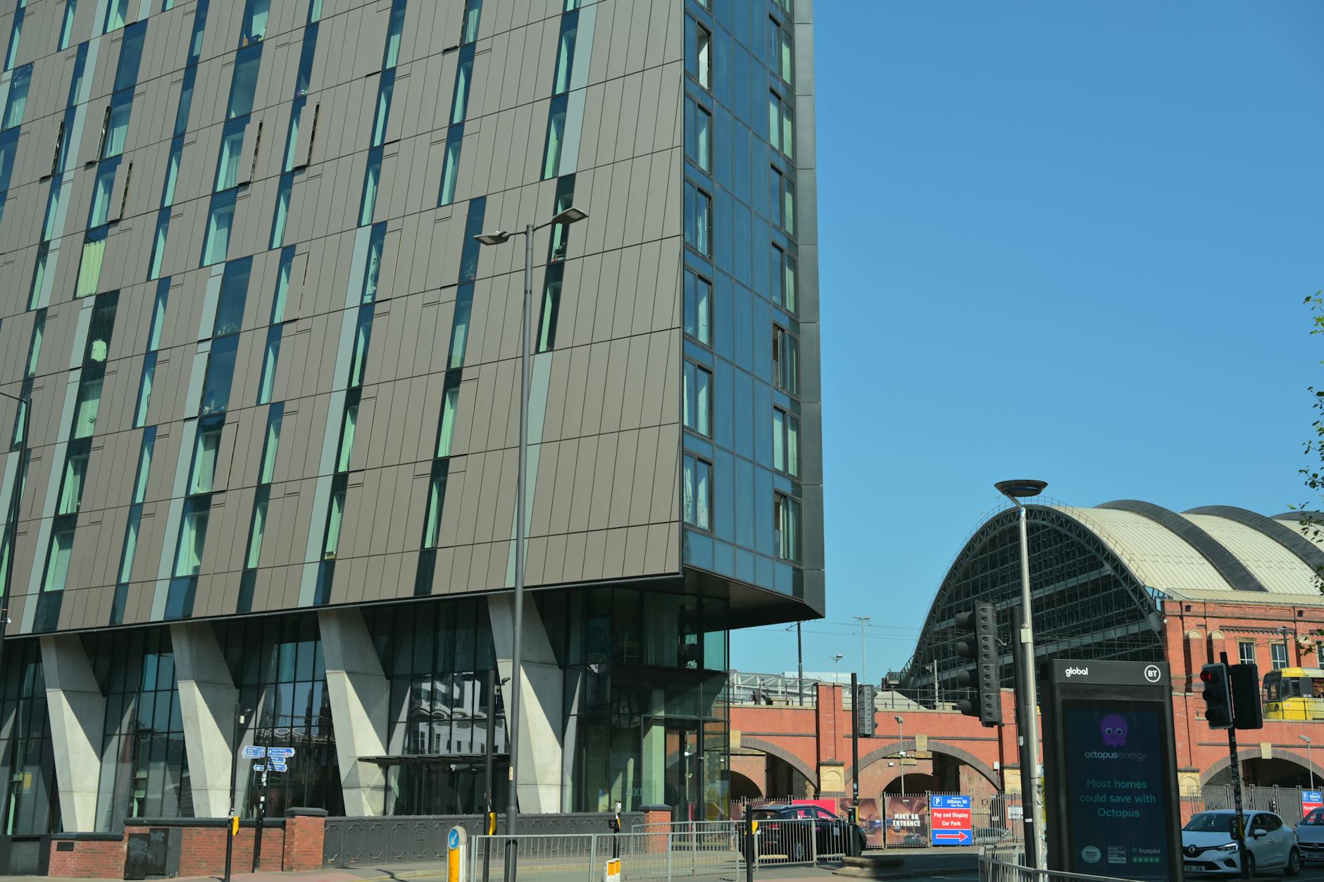Modern building beside a Manchester train station under blue sky