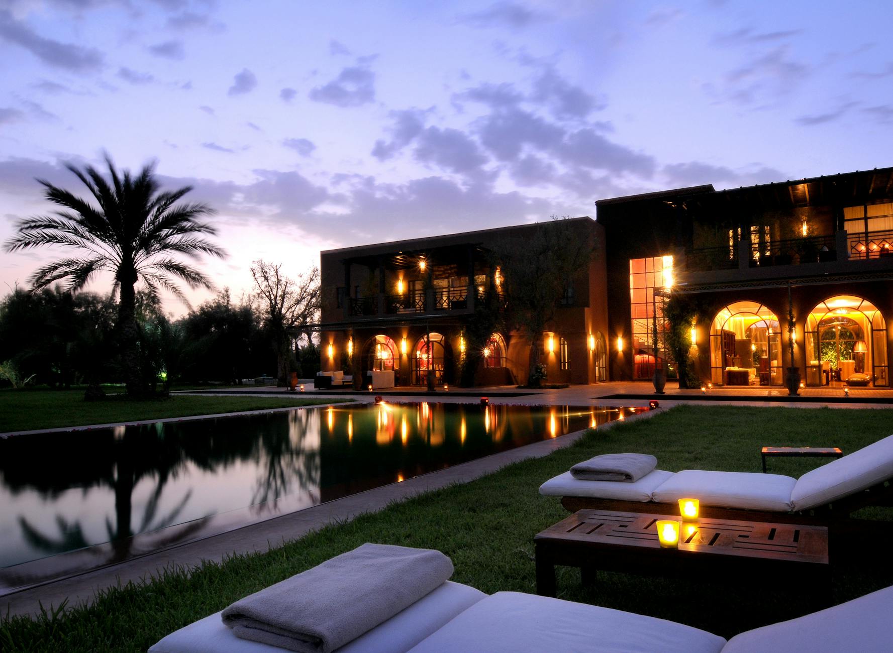 Illuminated Marrakech hotel facade and pool at dusk