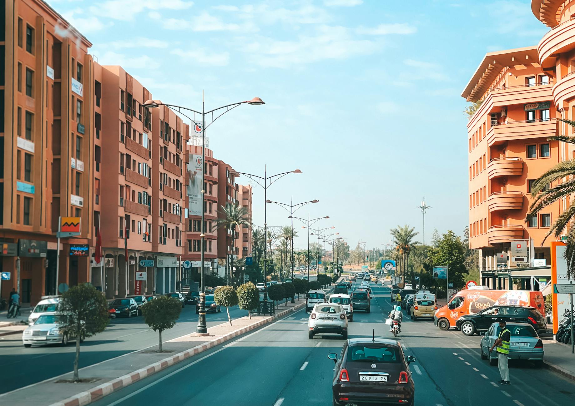 Street in Marrakech with traffic and ochre buildings under a blue sky