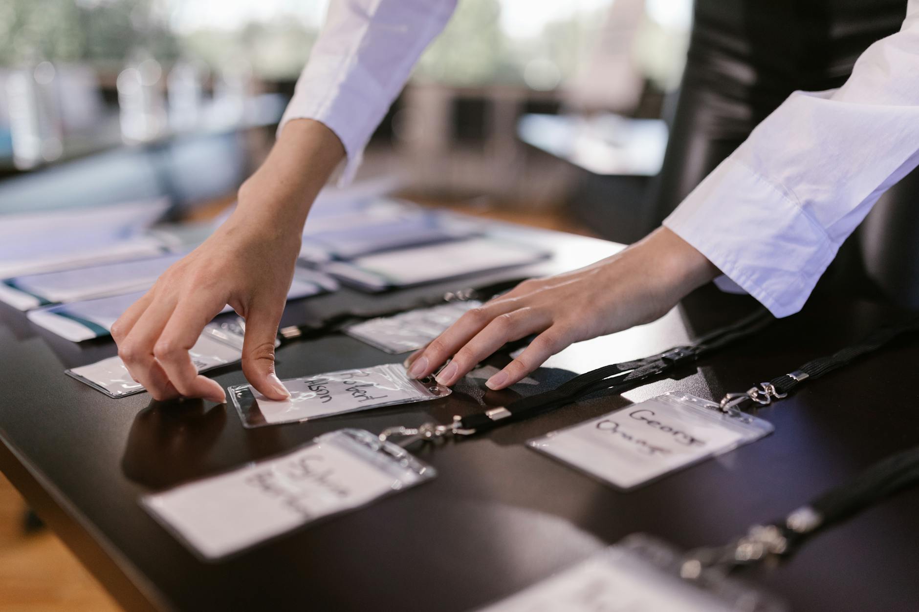 Hands arranging conference name tags on a table