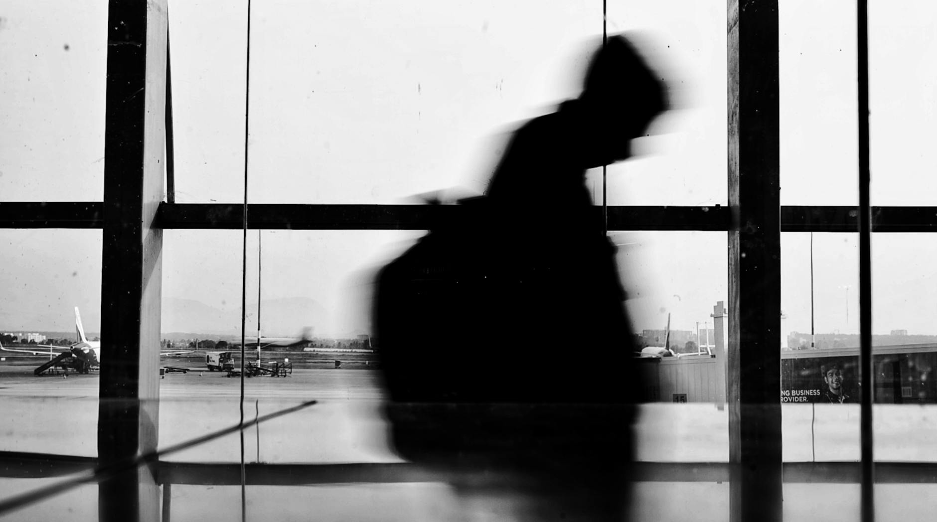 Traveler walking through an airport terminal with aircraft visible outside