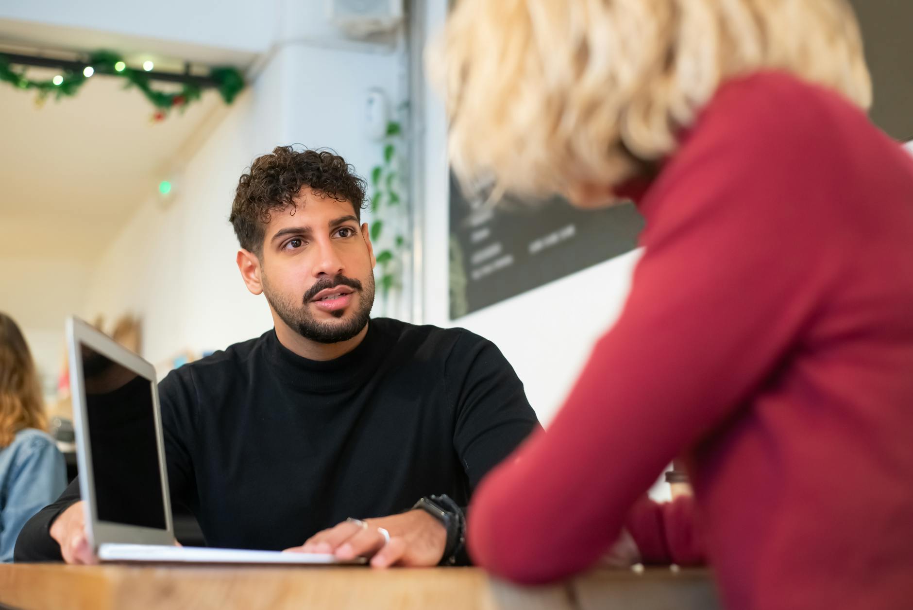 Two professionals discussing work over a laptop at a cafe table
