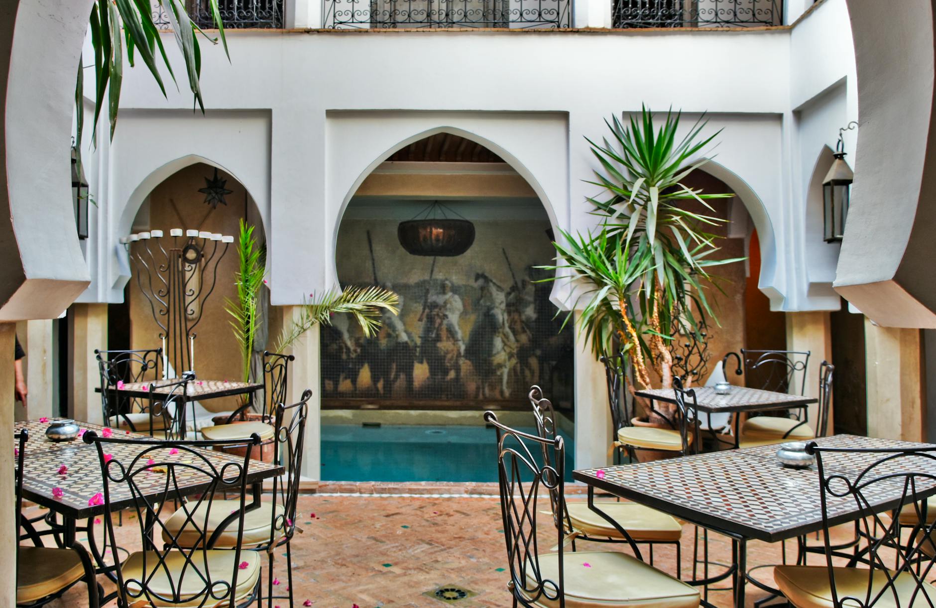 Moroccan courtyard hotel space with pool, tables, and ornate decor