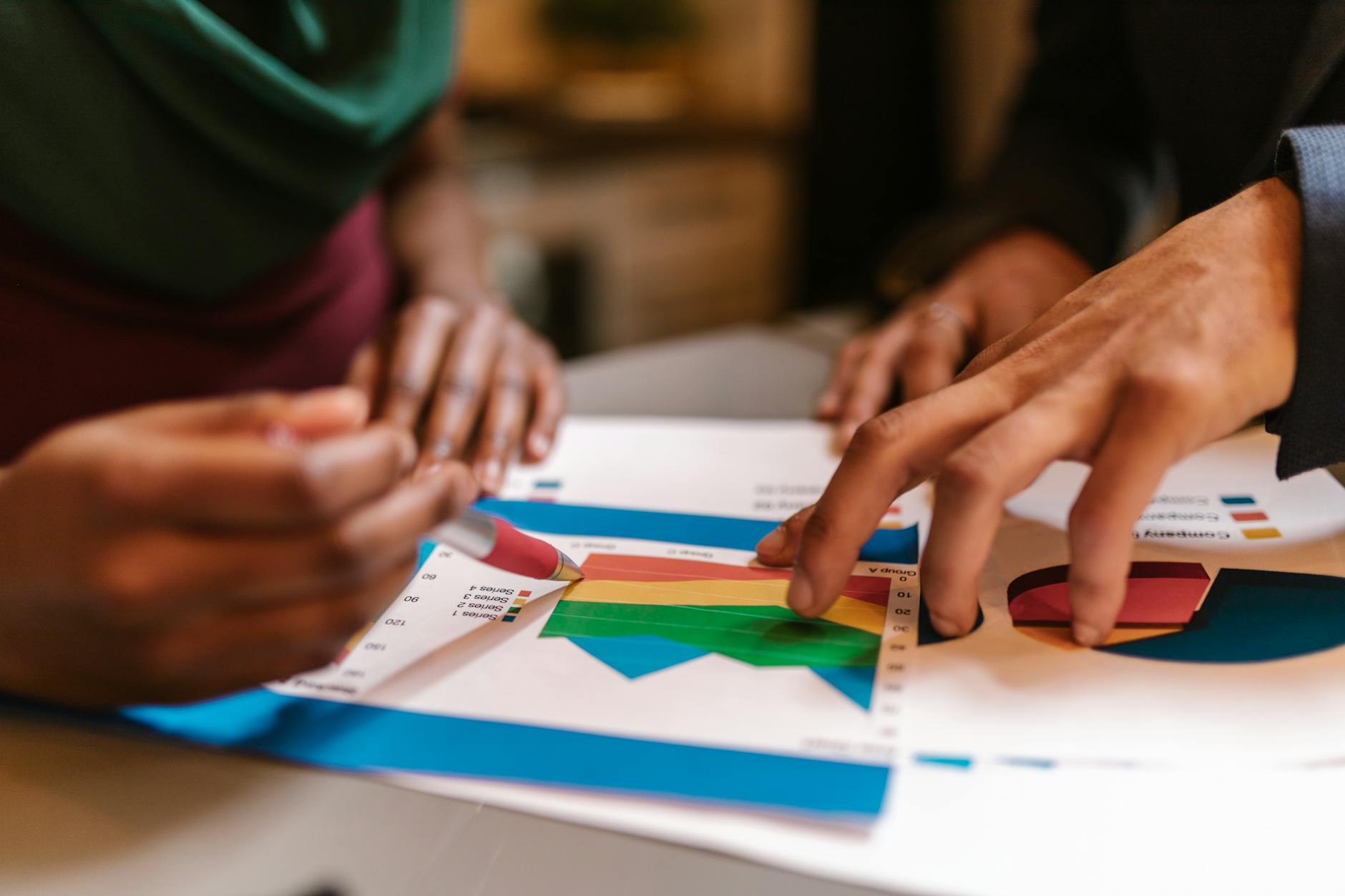 Hands reviewing printed charts and documents during a business meeting