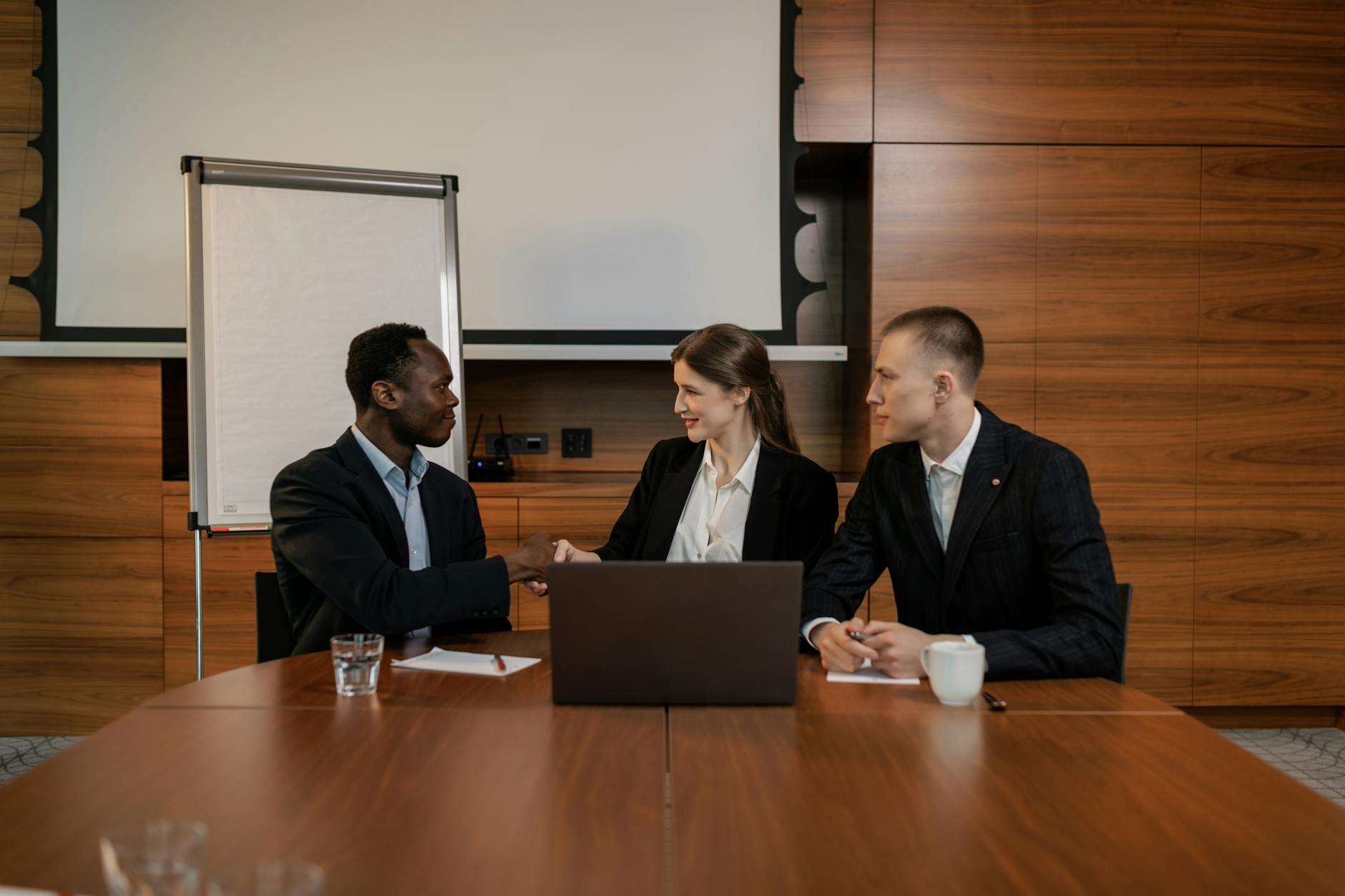 Professionals in business attire shaking hands during a meeting