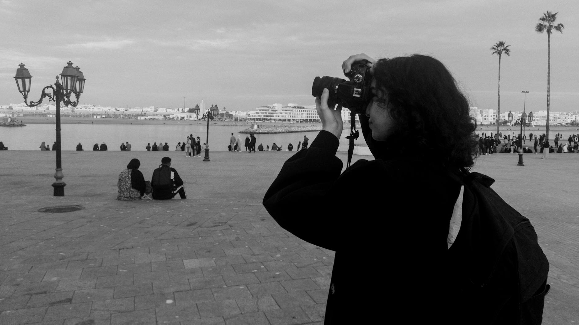 Photographer capturing a Moroccan cityscape with people and palm trees
