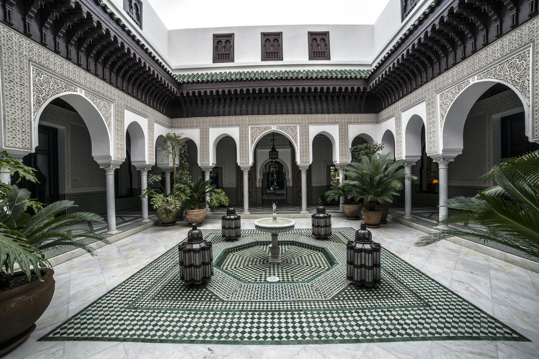 Ornate Moroccan courtyard with arches, fountain, and mosaic floor