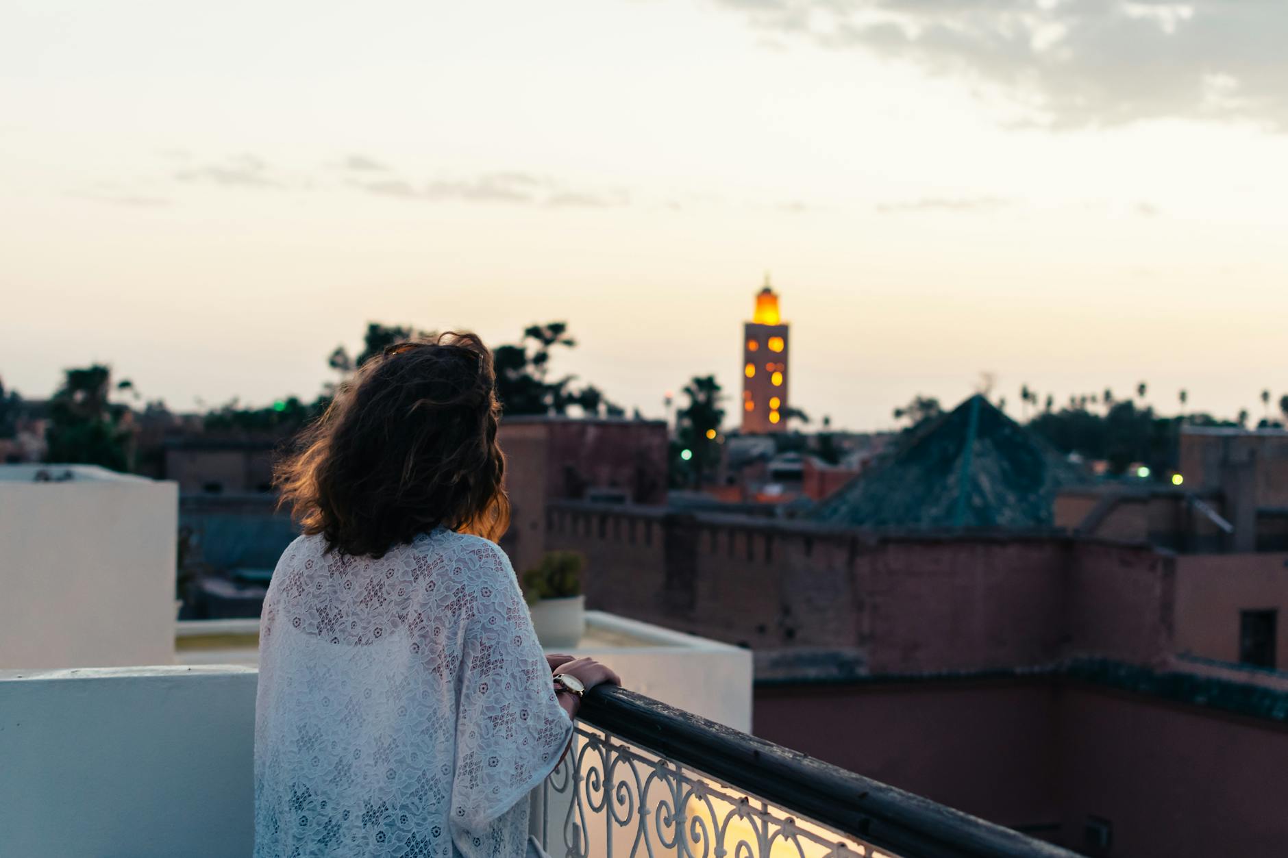 Traveler looking over the Marrakech skyline from a balcony at sunset
